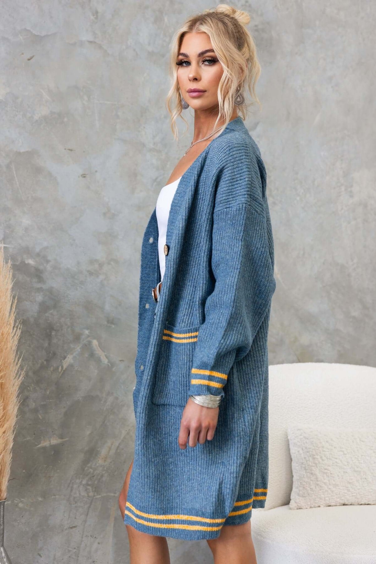 Woman modeling a blue longline cardigan with a V-neckline, button-up front, and pockets, styled with casual layers.