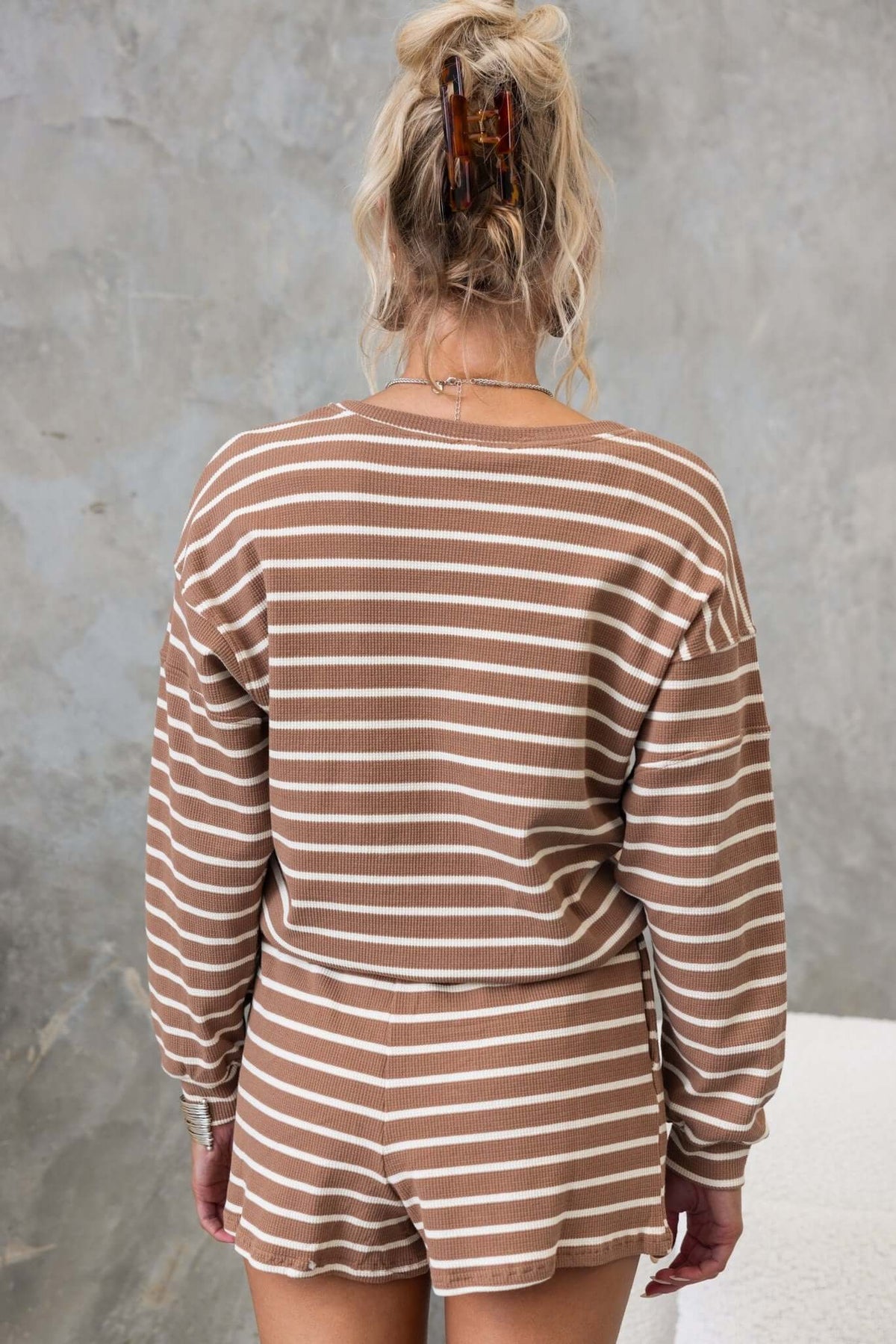 Back view of a woman wearing a striped brown jumper, showcasing a relaxed fit and textured cotton material.