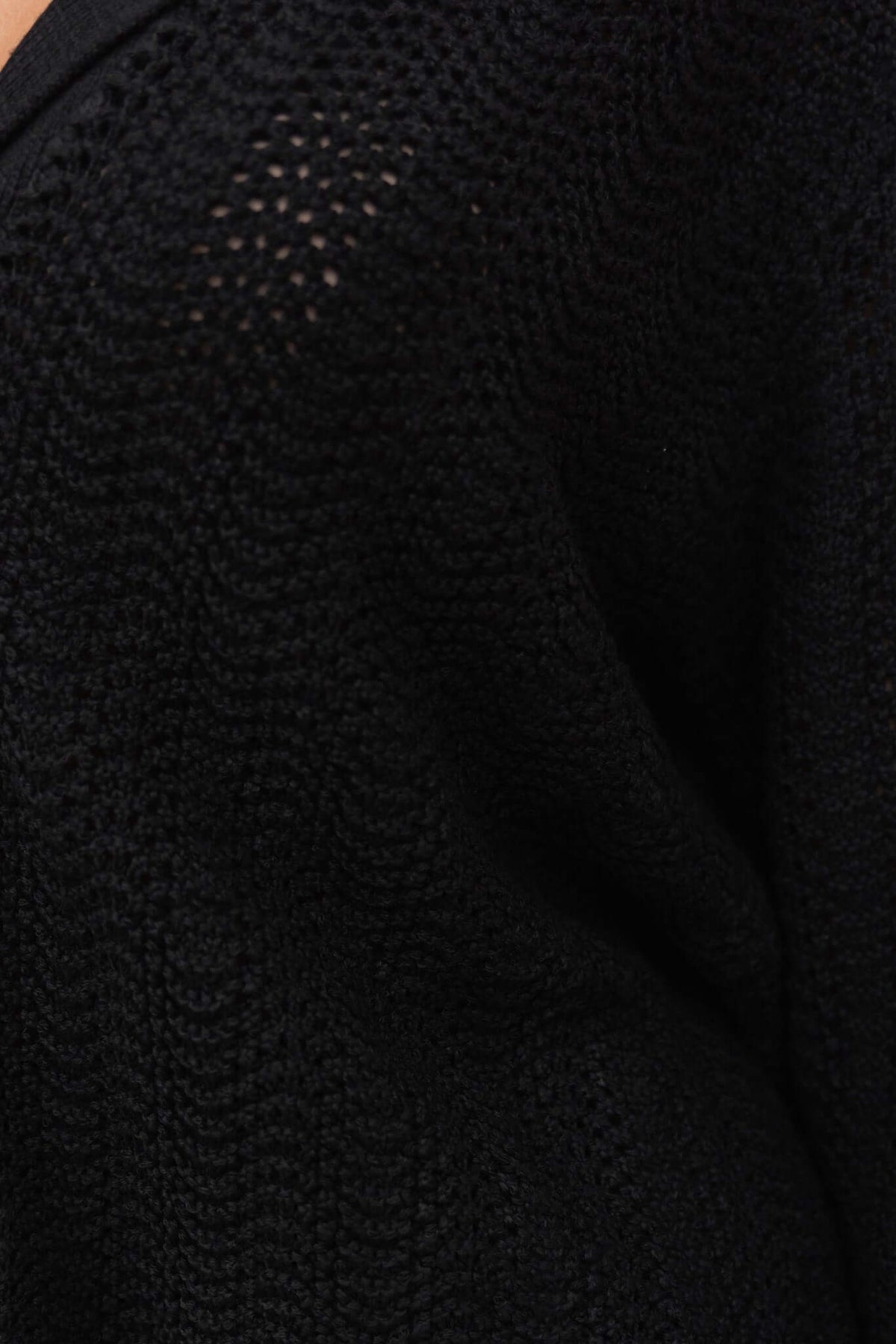 Close-up of black knit material showing semi-open weave texture of Moline Shirt, highlighting its stylish fabric.