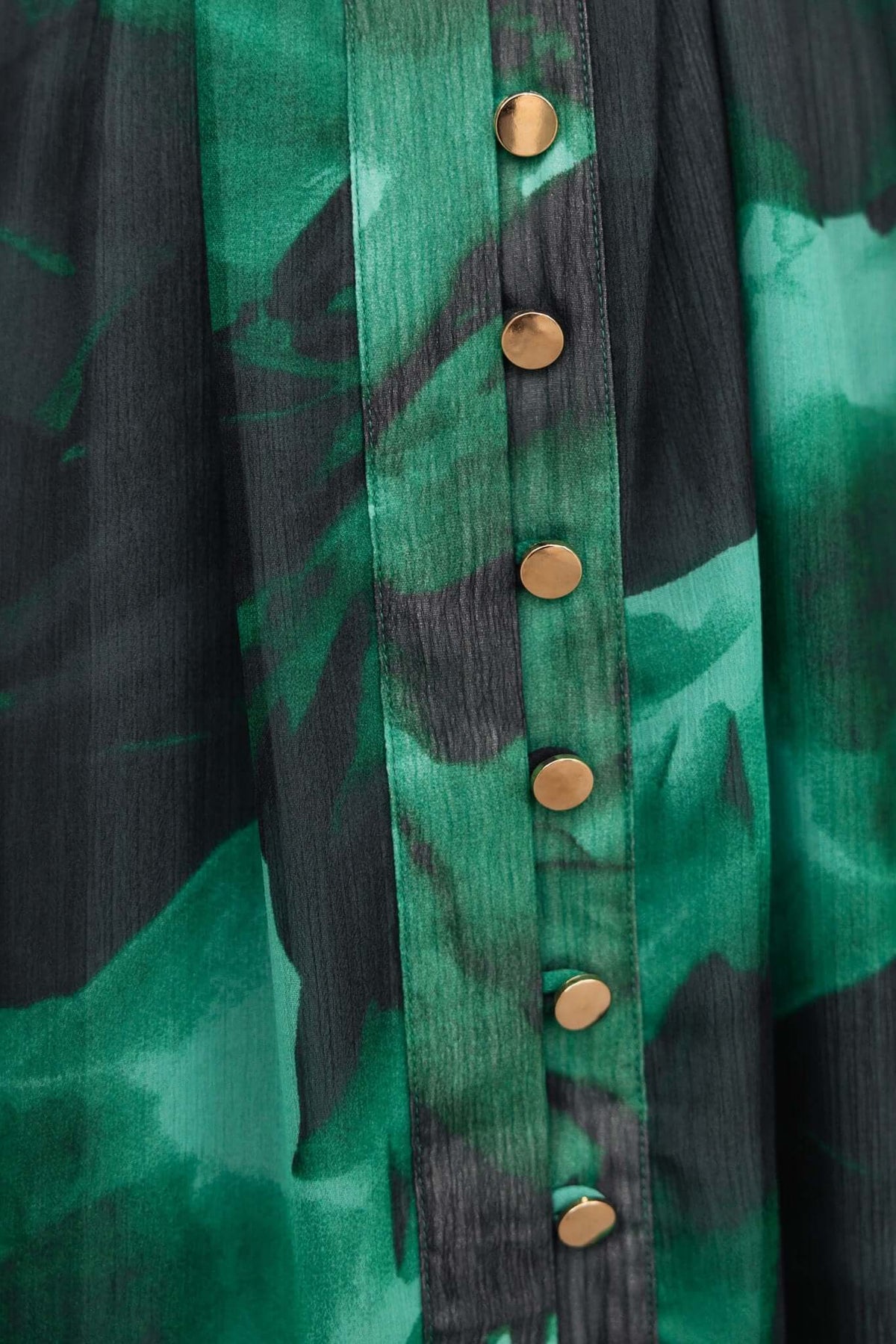 Close-up of Orazio Dress showing high neckline, button-up front, and green chiffon fabric with gold buttons.