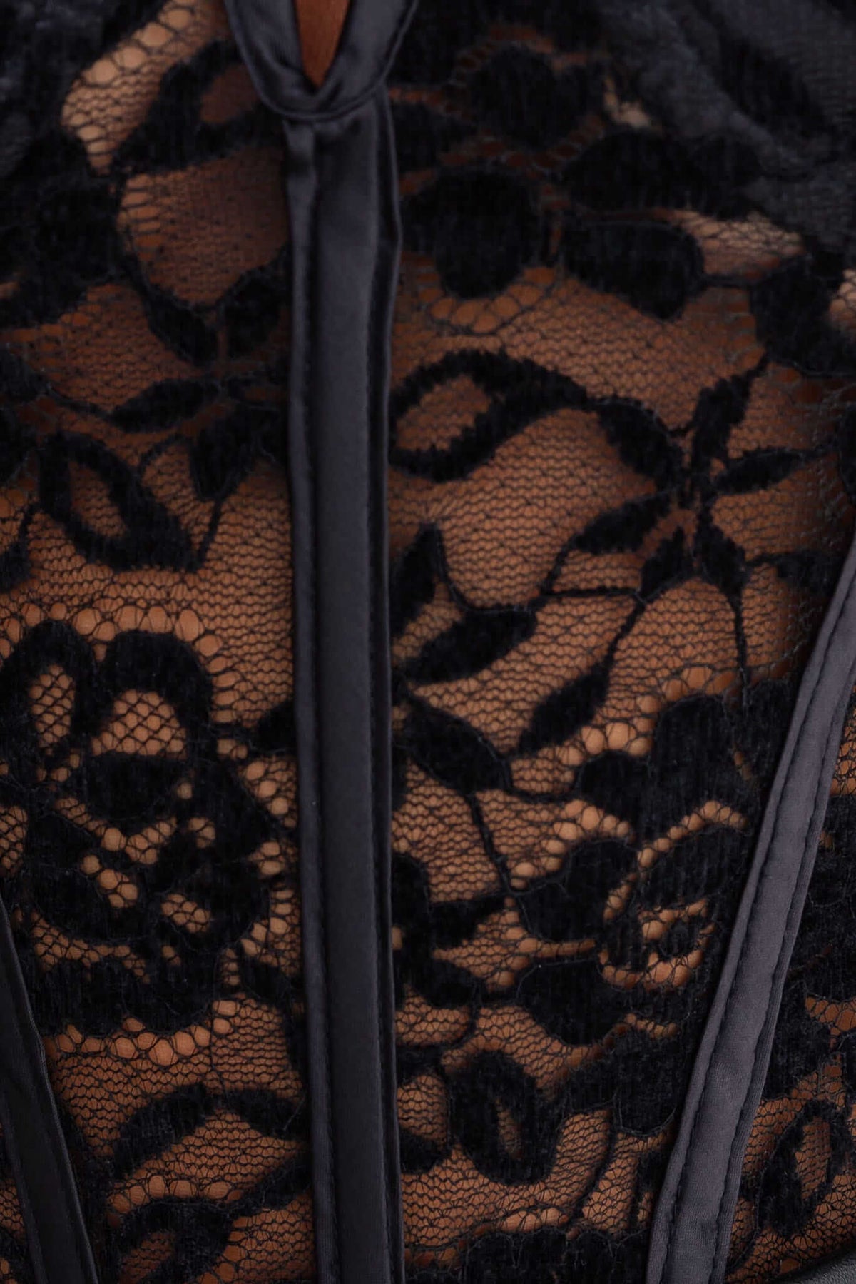 Black lace bodysuit detailing featuring adjustable straps and elegant floral patterns.
