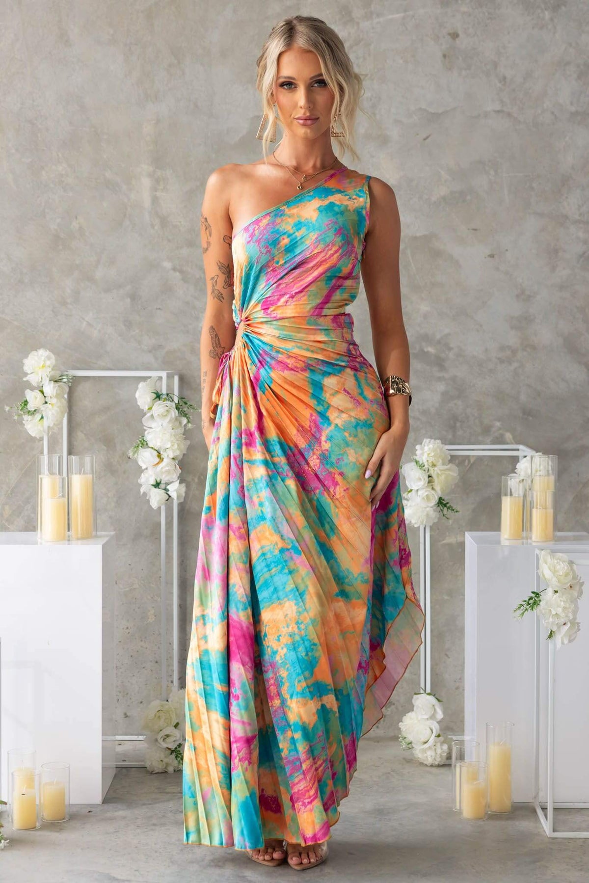 Model wearing a colorful Tejano maxi dress with one-shoulder neckline and elegant twist detail.