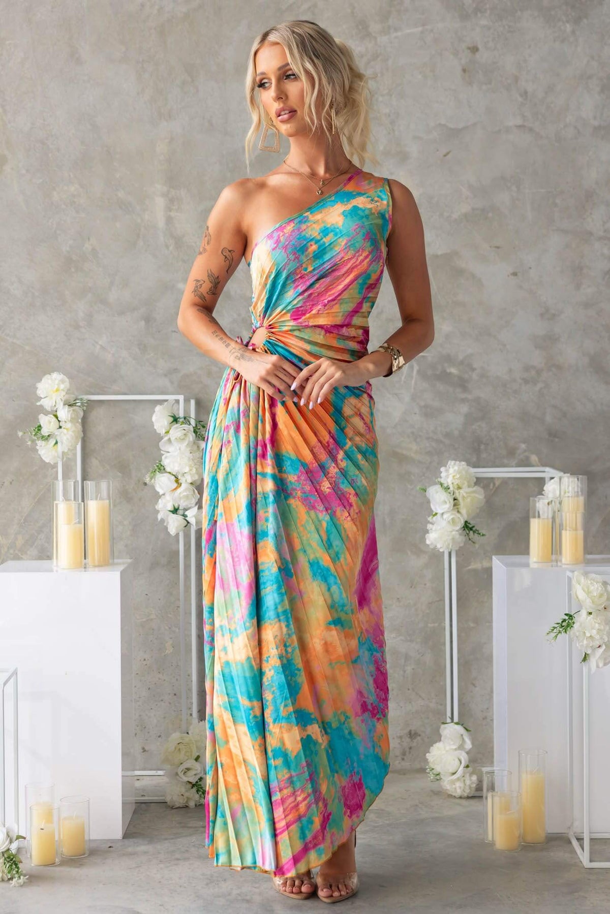 Colorful Tejano maxi dress with one-shoulder neckline and cut-out waist, styled against a minimalistic background.