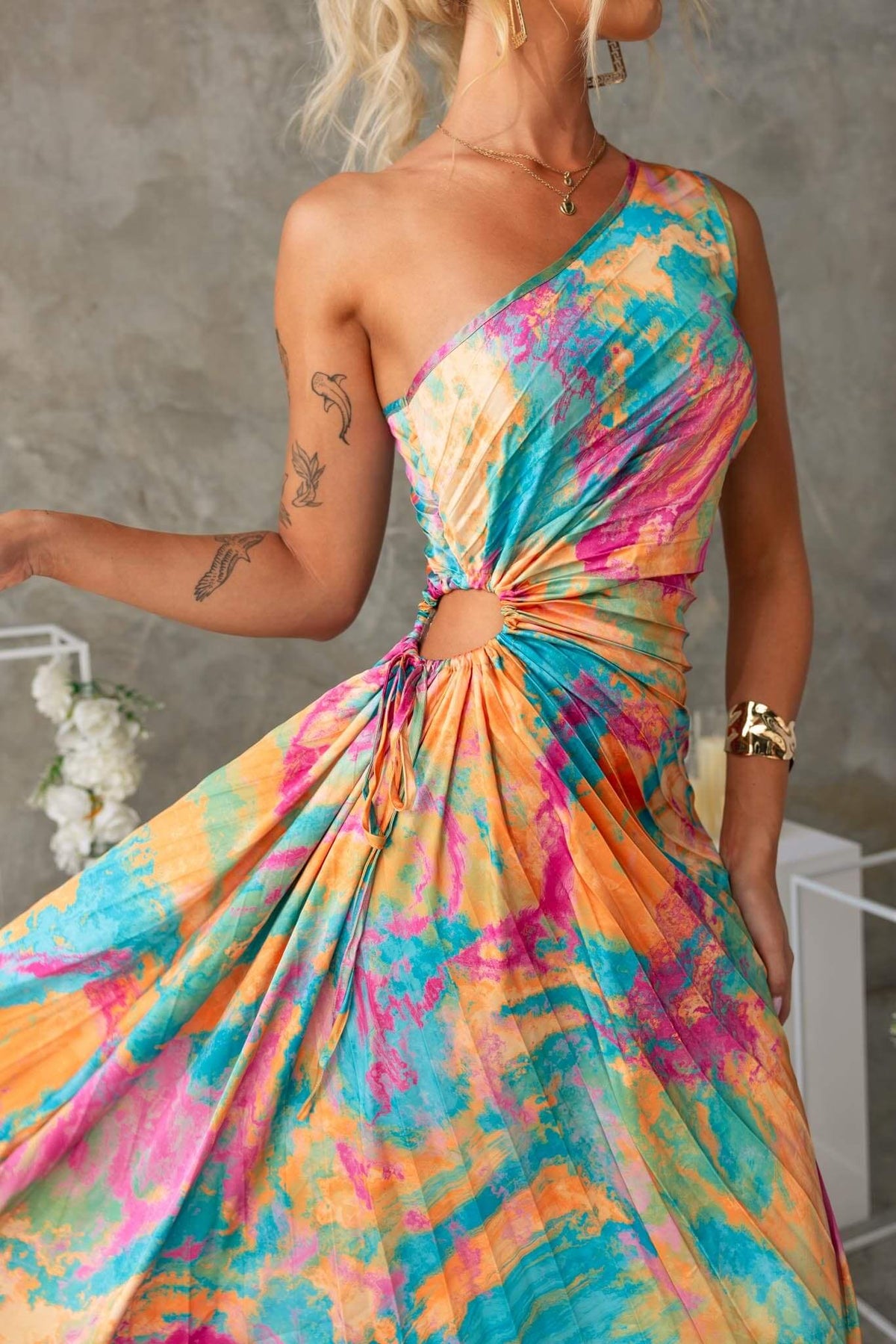 Colorful Tejano maxi dress with one-shoulder neckline, cut-out waist, and adjustable tie detail, perfect for summer events.