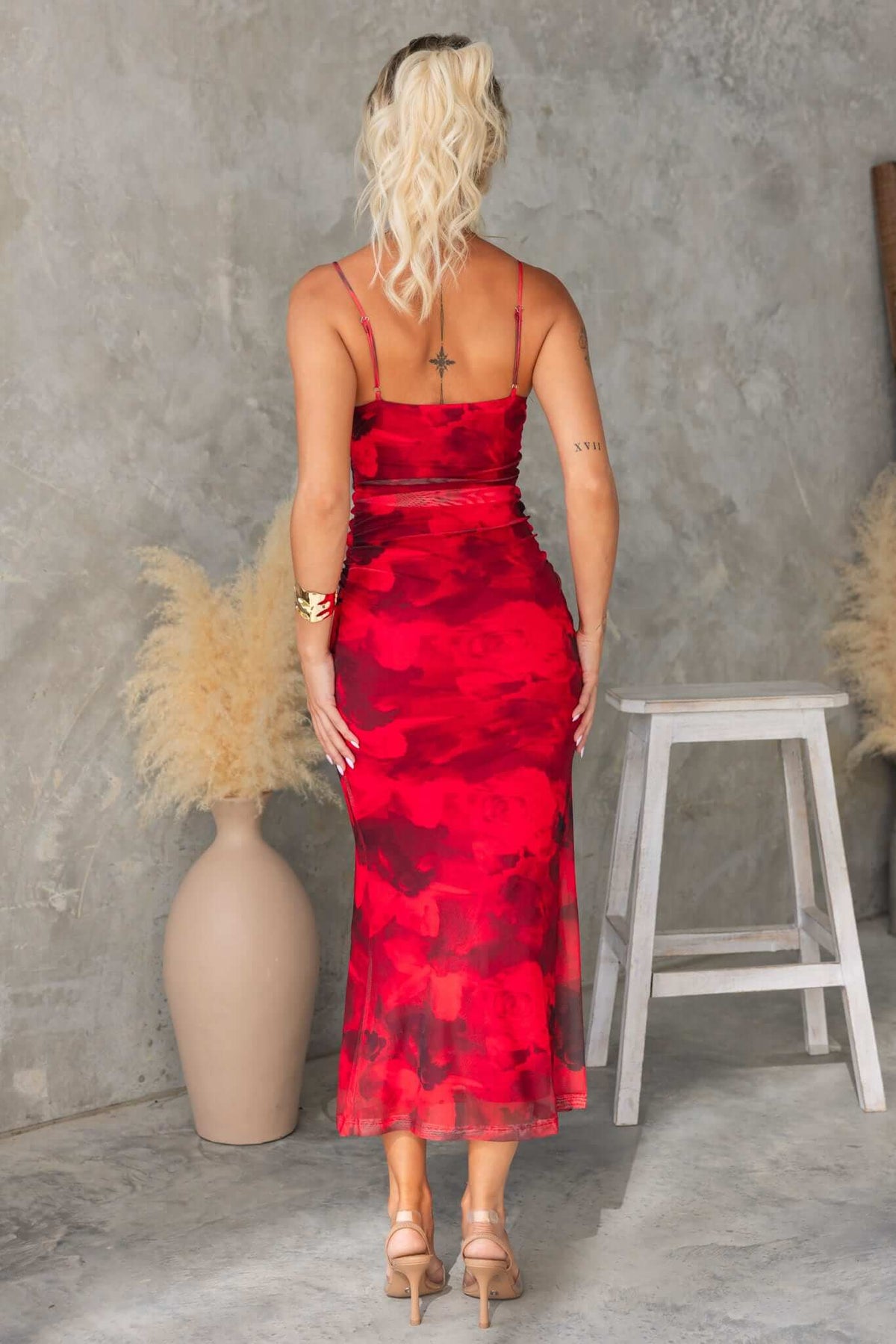 Back view of a woman in a red floral Midi Dress with adjustable straps, showcasing its fitted style.
