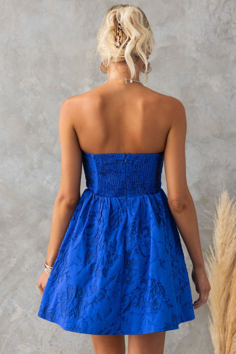 Back view of the Stole My Heart Dress, a strapless embossed print dress in vibrant blue with a flared skirt.