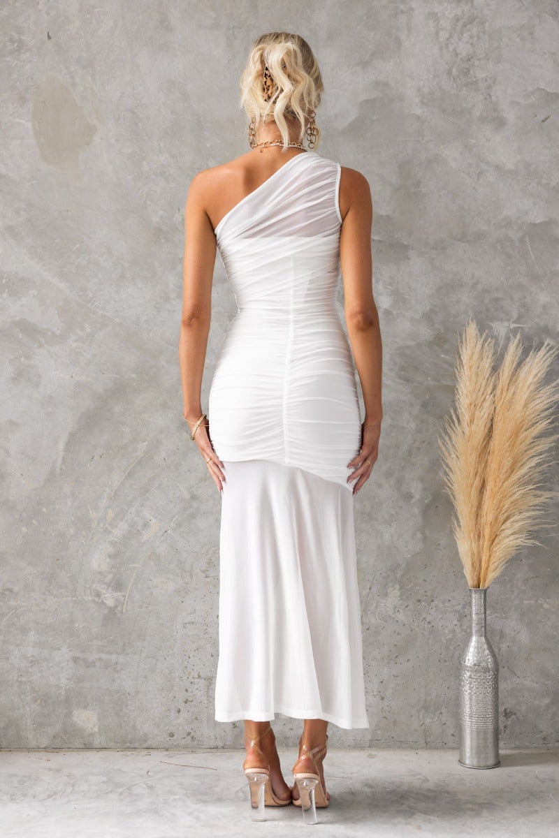 Back view of a white bodycon one-shoulder maxi dress with a mesh overlay and ruched detailing.