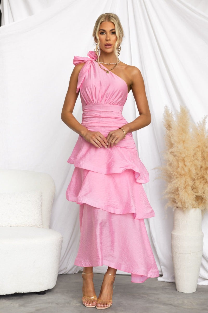 Taylah models a pink one-shoulder Sherbert midi dress with a ruffle hem and tie detail, showcasing a chic summer look.