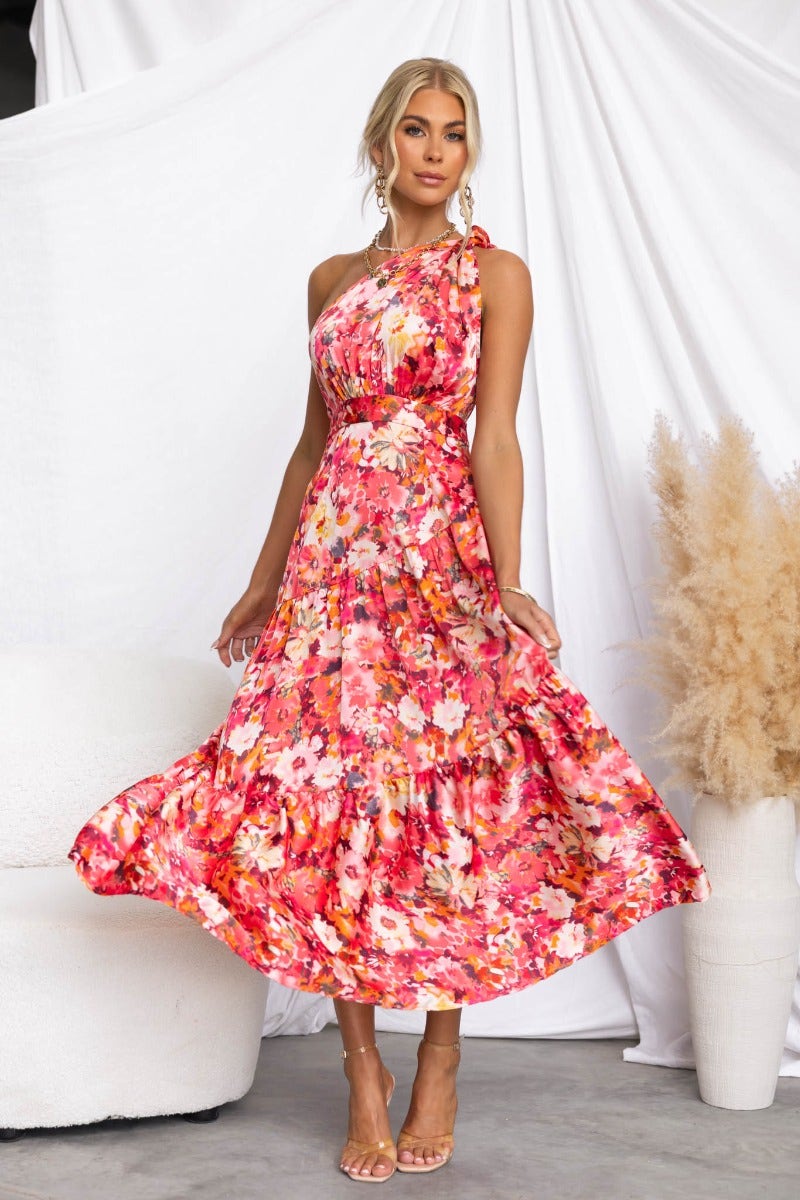 Carmen Midi Dress featuring a floral print, one-shoulder neckline, and flowy skirt, styled with sandals.