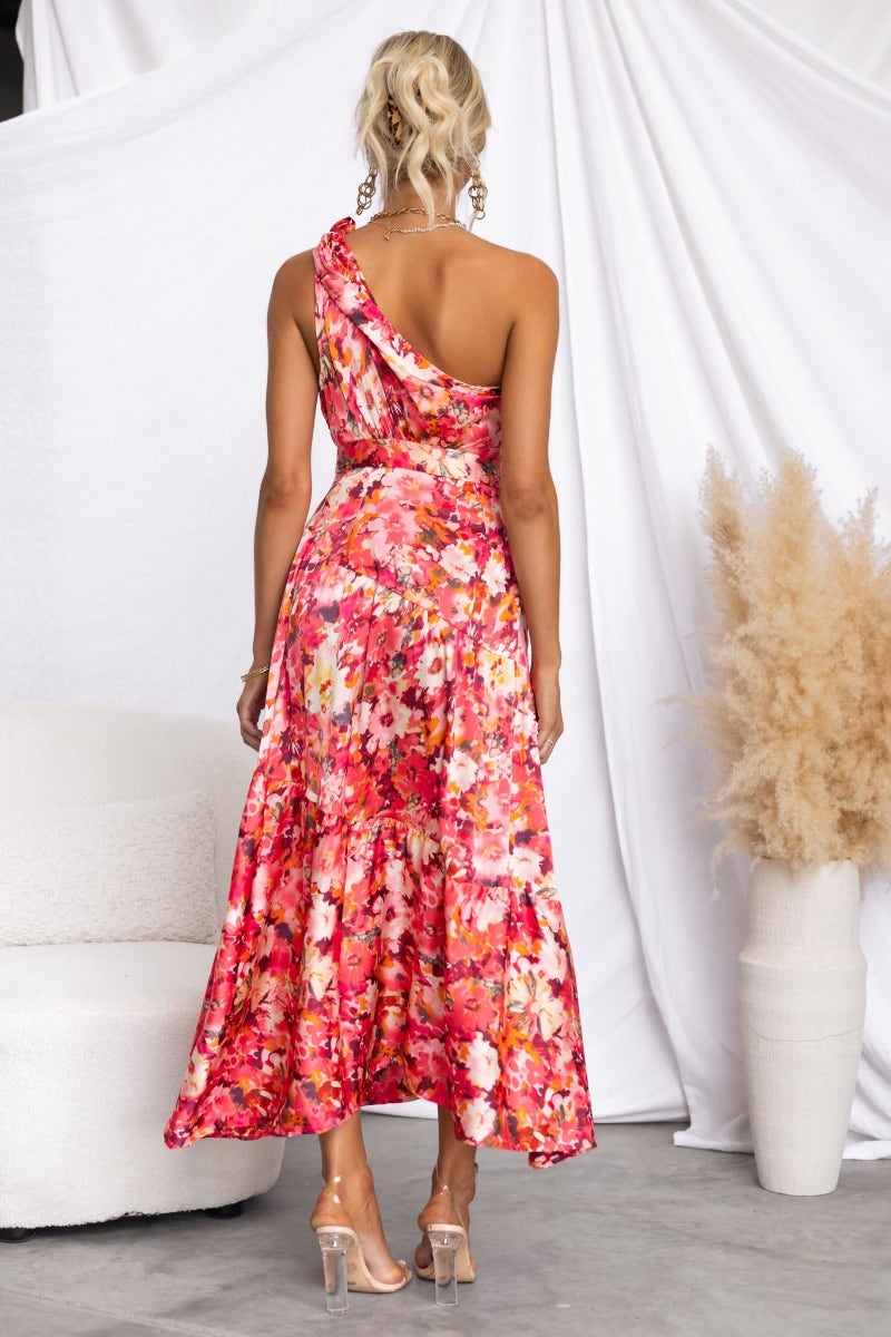 Back view of Carmen Midi Dress featuring a floral print, one-shoulder design, and flowing skirt.