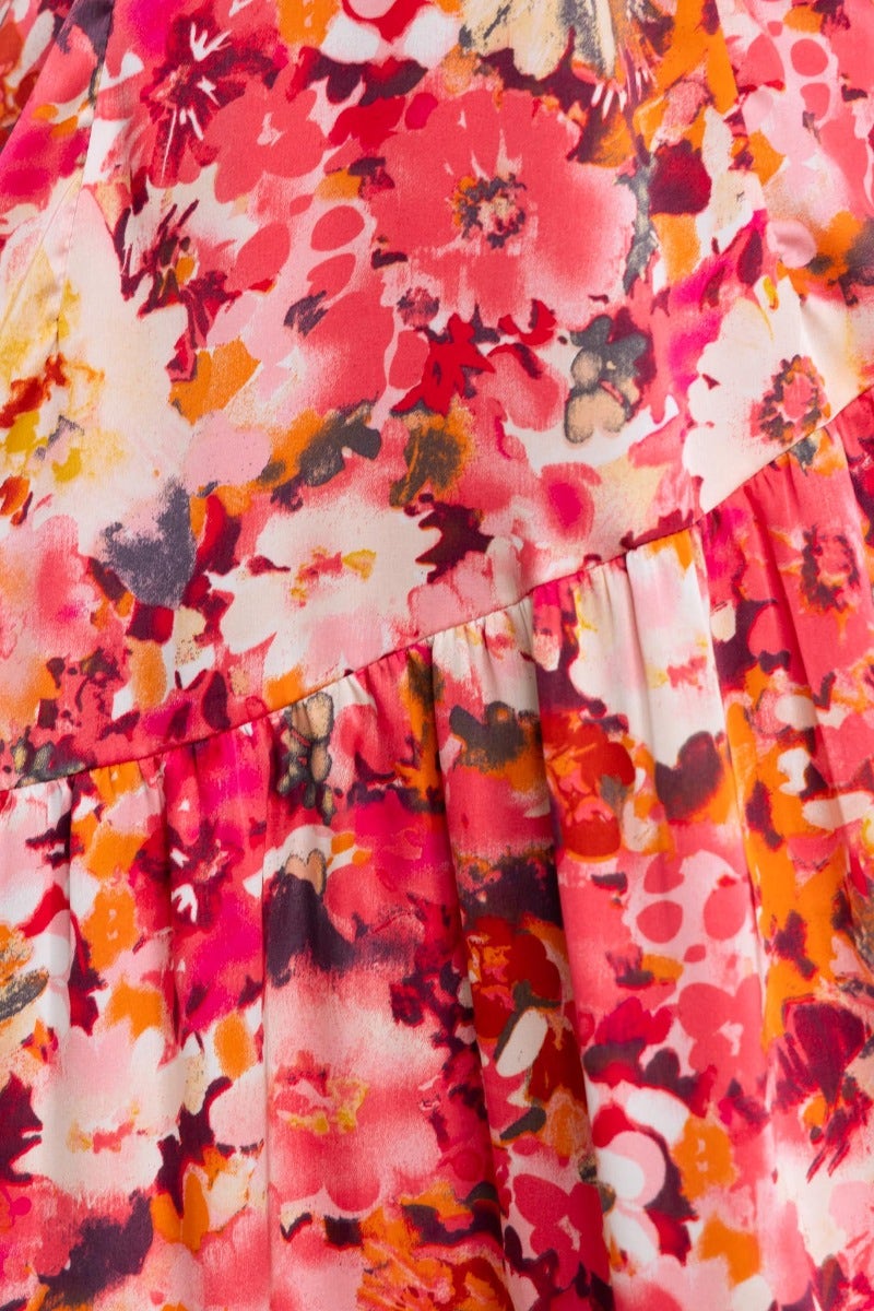 Close-up of floral print details on the Carmen Midi Dress featuring vibrant pink and orange hues.