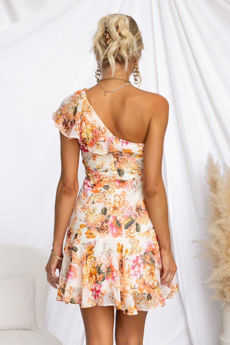 Model wearing a floral print Uze Dress with one-shoulder neckline and frill detail.