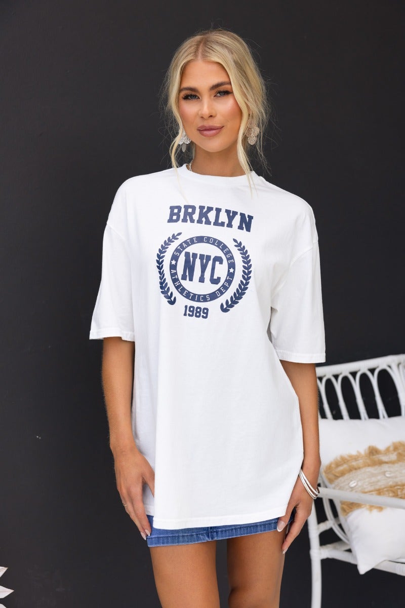 Model wearing oversized white Duke Top tee featuring 'BRKLYN NYC' print for a stylish casual look.