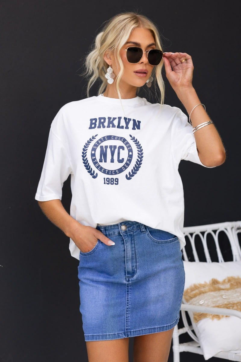 Model wearing Alley Denim Pencil Skirt with graphic tee and sunglasses, showcasing front and back pockets.