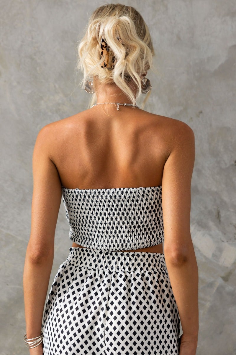 Back view of a model wearing an Oscar Top, a strapless black and white printed crop top with anti-slip design.