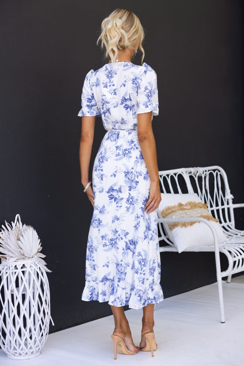 Model wearing Oceanside Wrap Midi Dress, showcasing floral design and high-low hem from the back.