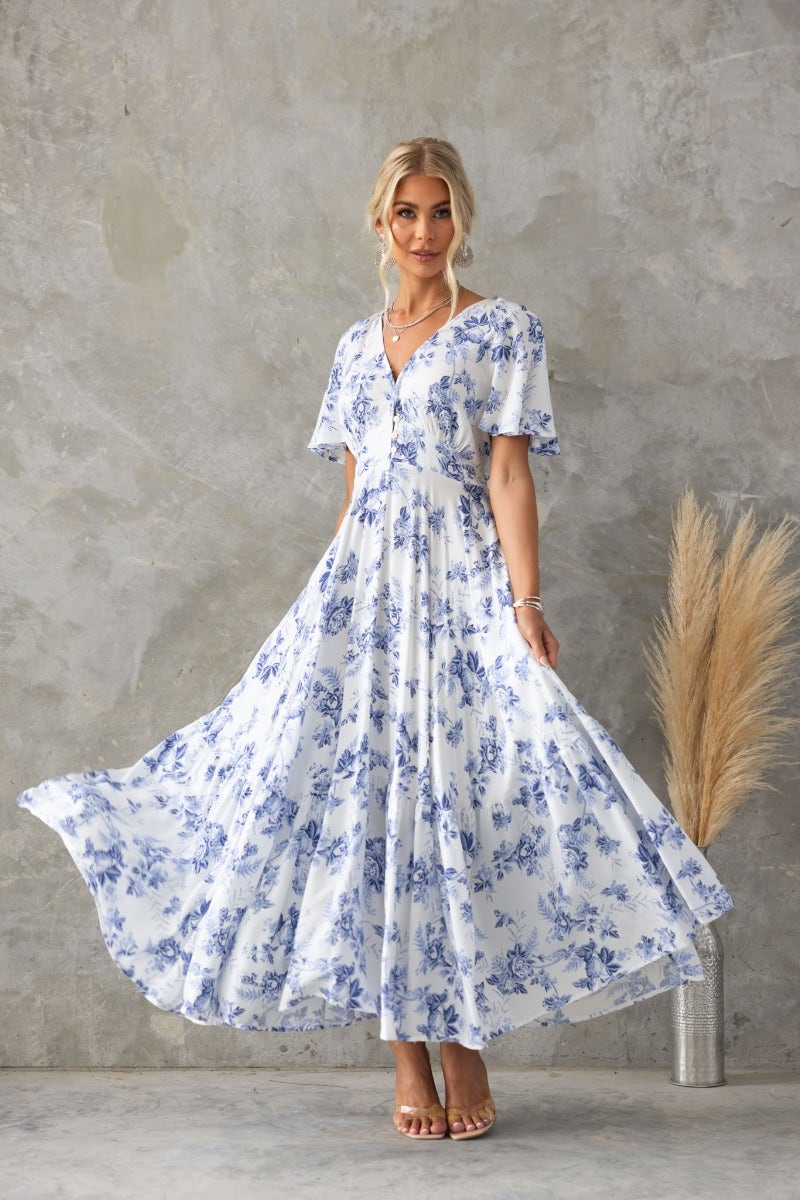 Nashville Maxi Dress featuring a floral print, V-neckline, and flowing silhouette, worn by a model against a textured background.