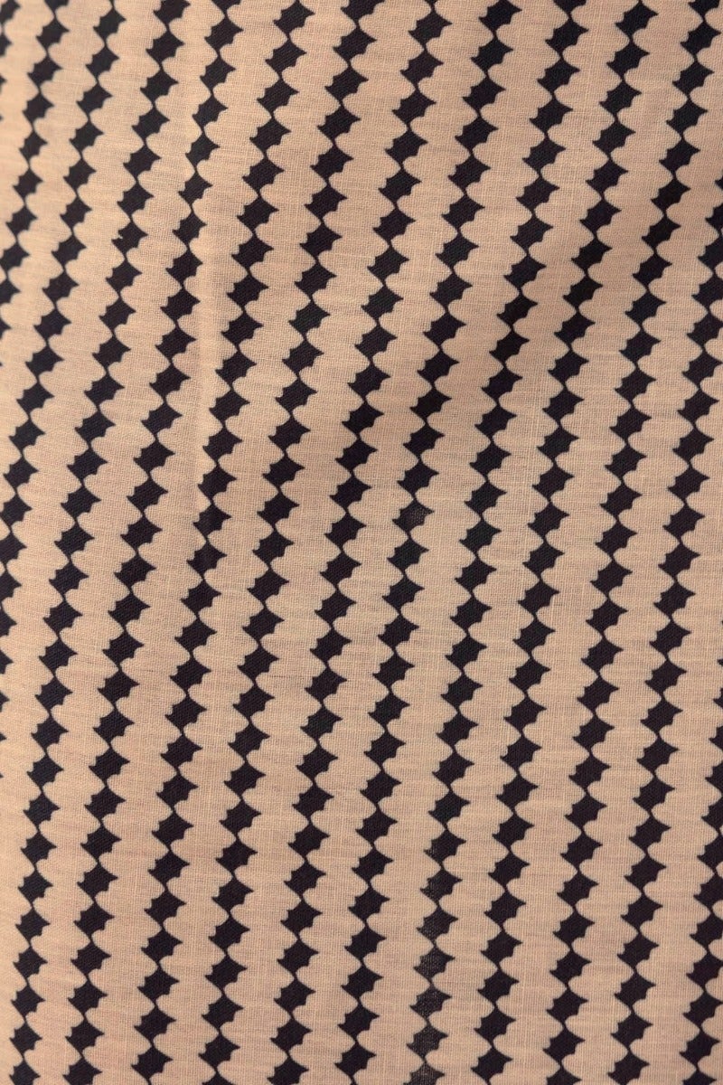 Close-up of beige fabric with a geometric black pattern, ideal for a stylish daywear collection.