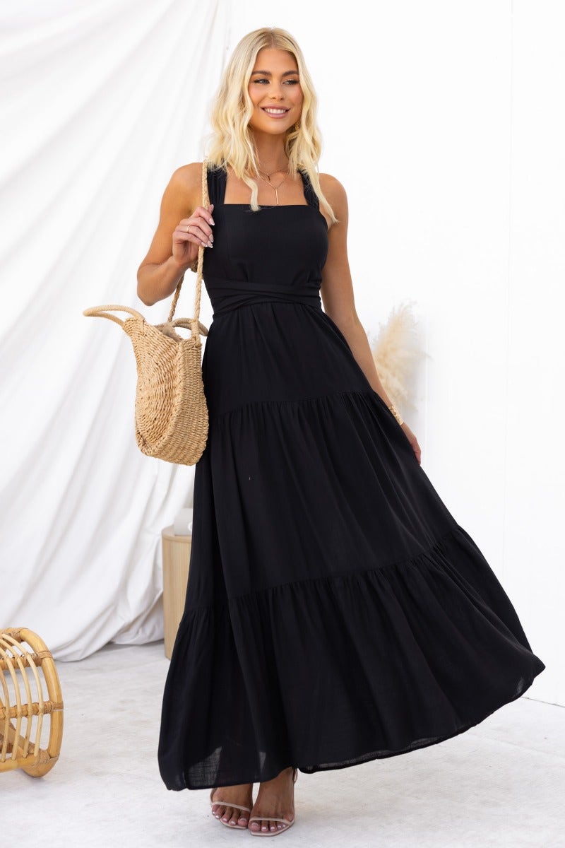 Model wearing Etsie Maxi Dress, a black halter maxi dress with pockets and a tiered design, perfect for summer outings.
