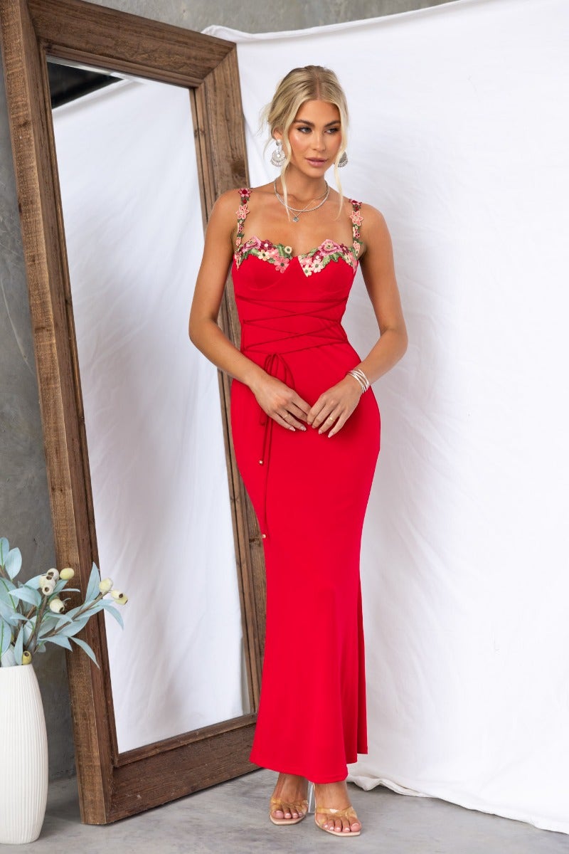 Model wearing a red bodycon maxi dress with floral trim and adjustable straps, perfect for elegant occasions.