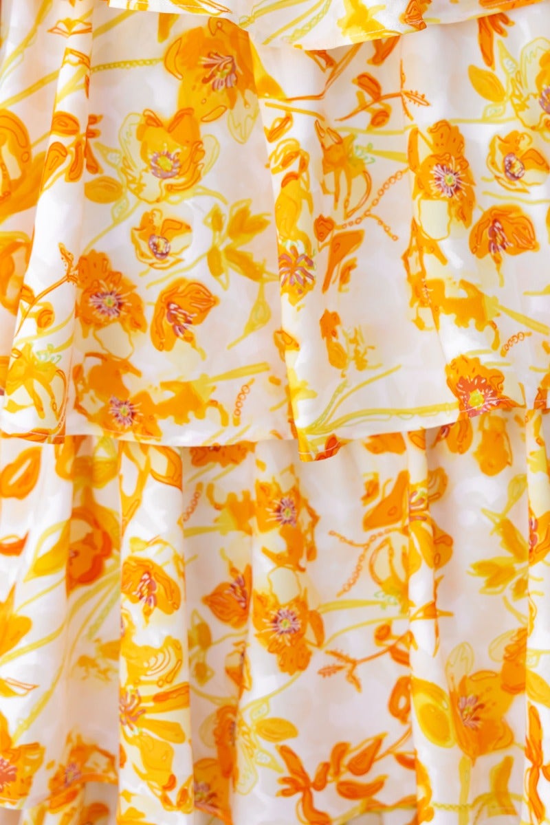 Close-up view of a floral print fabric featuring vibrant orange and yellow flowers on a white background.