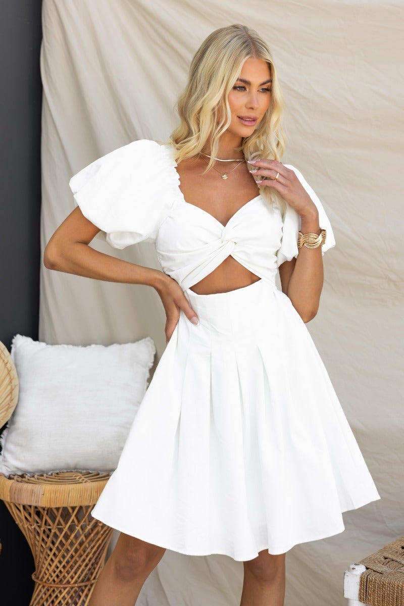 Elegant white olive dress featuring puff sleeves, twist detail at bust, cut-out under bust, and pleated skirt.