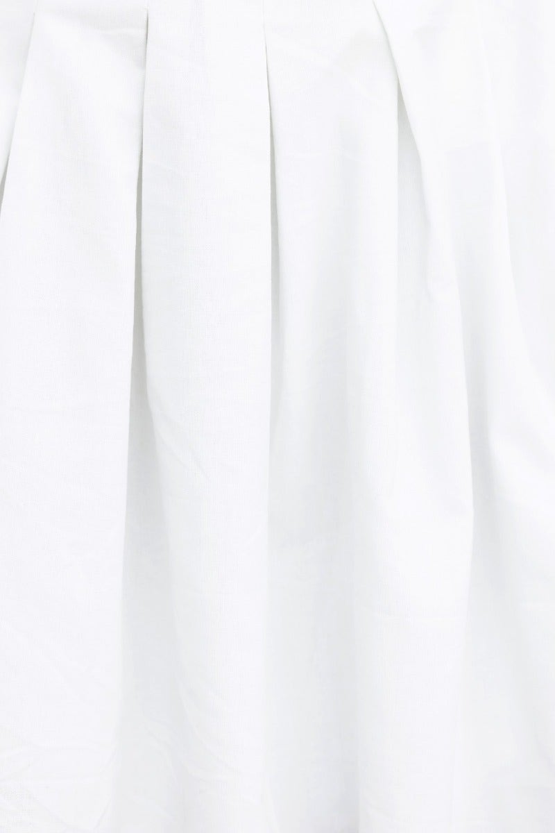 Close-up of white pleated fabric showcasing texture and drape of an elegant dress garment.