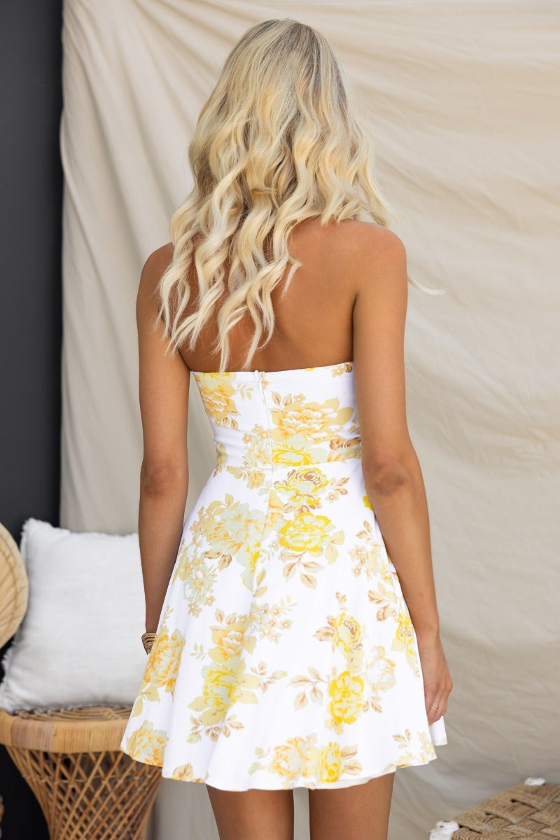 Back view of the Honesty Dress, a strapless floral print dress in white and yellow with a flared skirt.