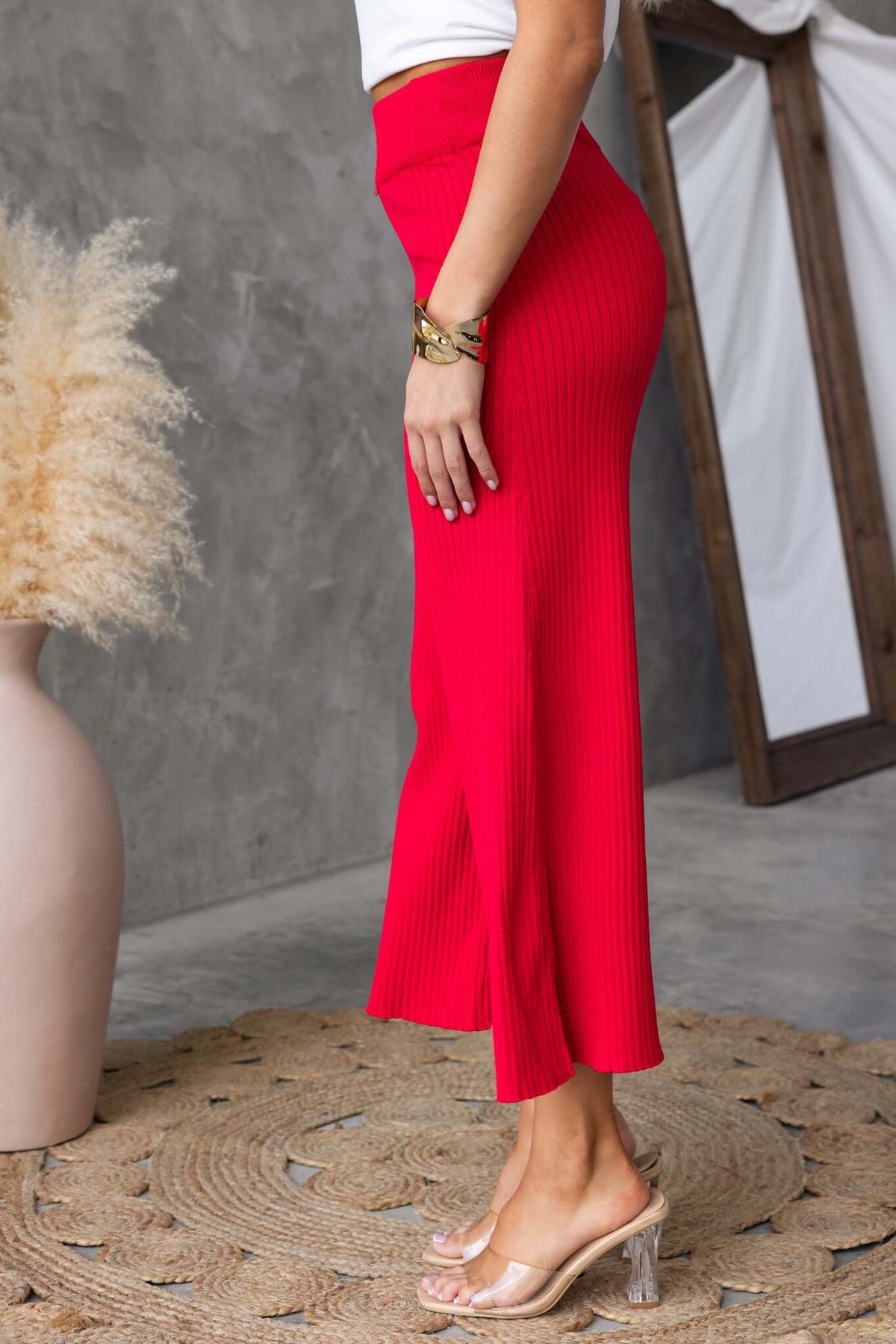 Model showcasing red Dipsie Pants with mid-high waist and ribbed knit material against a textured background.