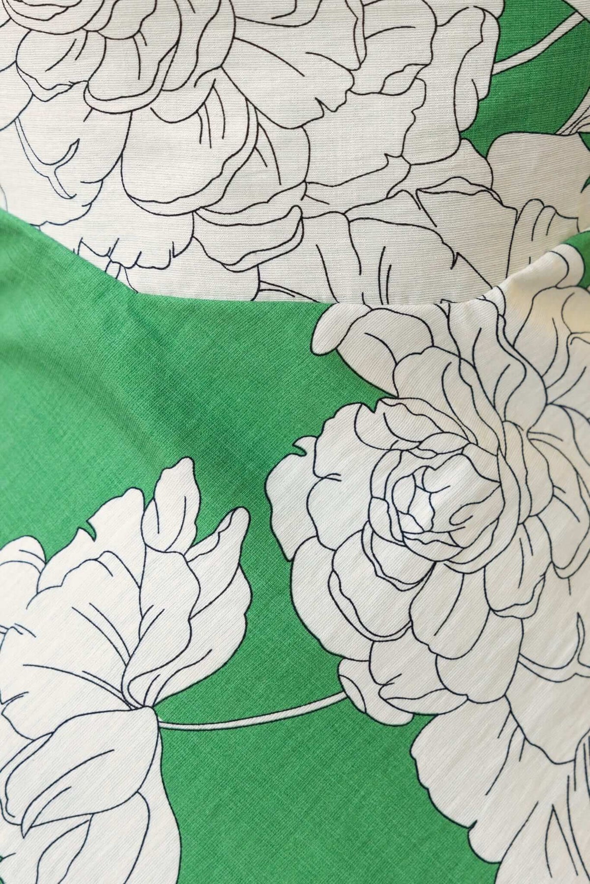 Close-up of floral design featuring white peonies on a vibrant green fabric, highlighting texture and colors of the Forbidden Love Maxi Dress.