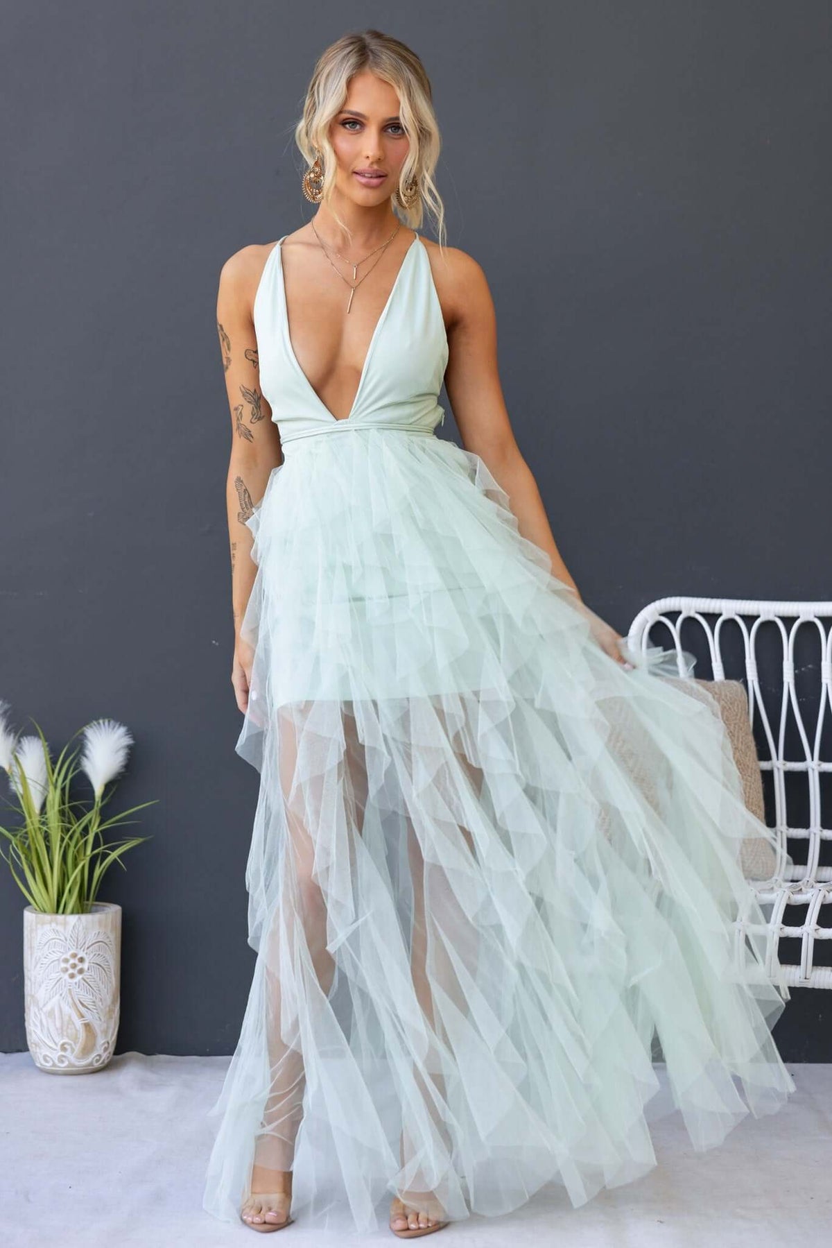 Model in a mint green Salinas maxi dress with a deep V-neckline and tulle ruffle skirt, perfect for special occasions.