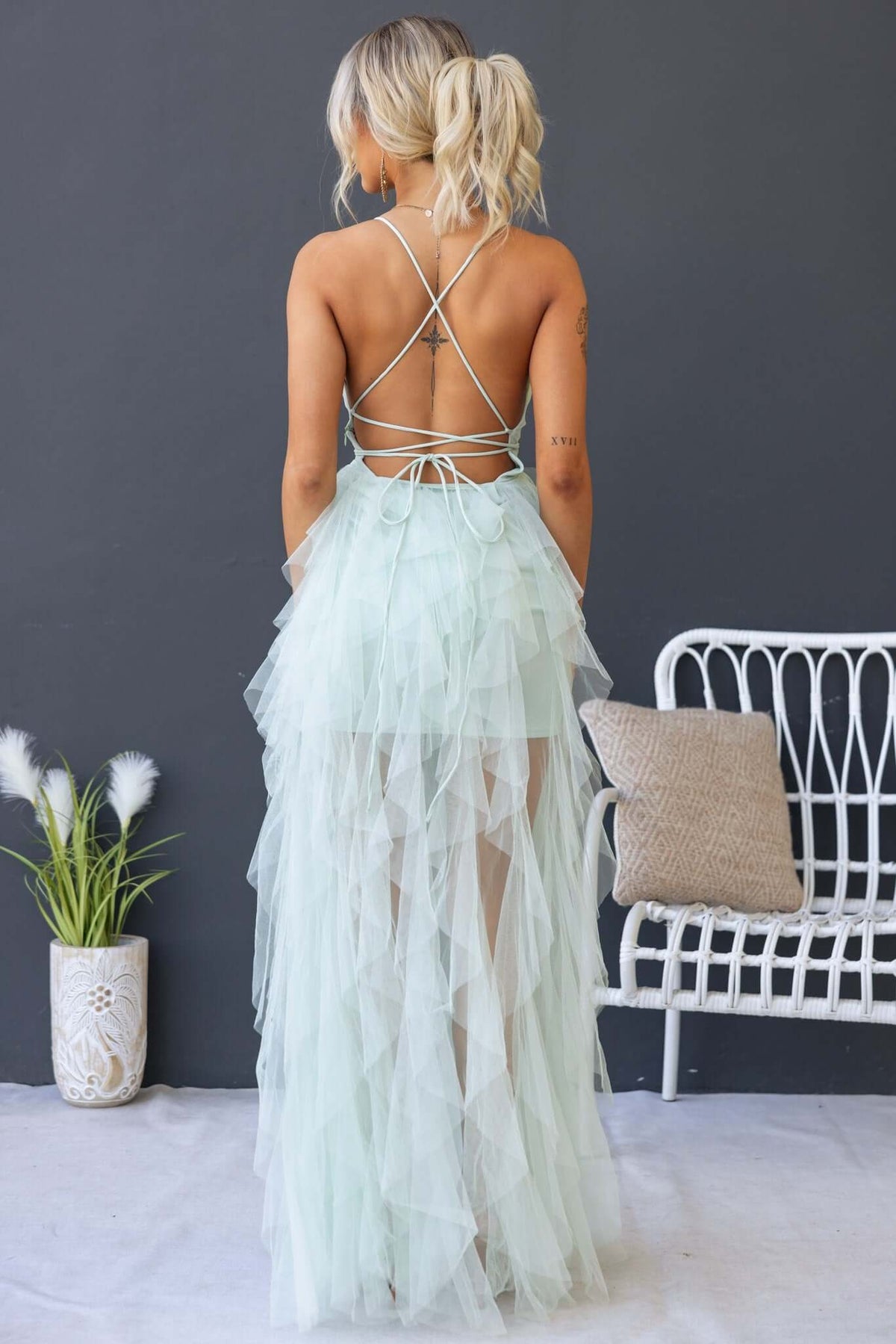 Back view of a woman in a mint green Salinas Maxi Dress with tulle ruffle skirt and lace-up detail.