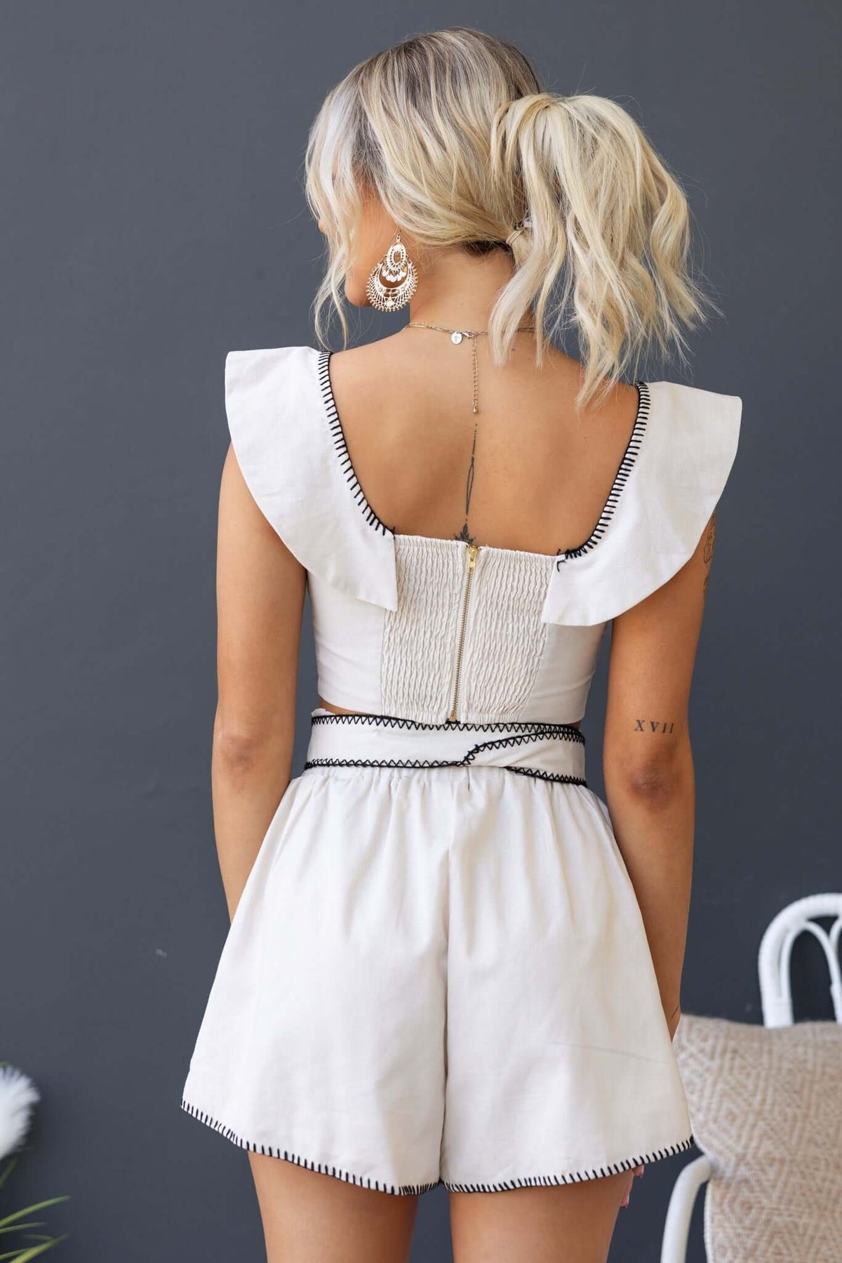 Back view of a woman wearing the Valerio Set featuring a scoop neckline, elastic waistband, and removable belt.