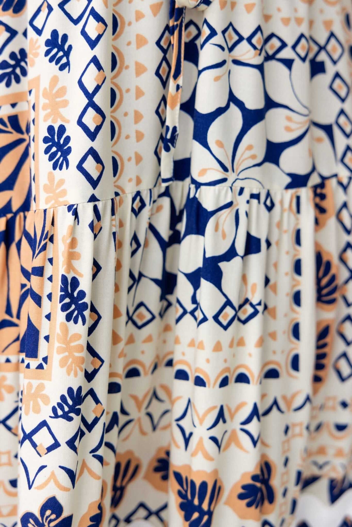 Close-up of the Virden Midi Dress featuring intricate floral and geometric patterns in navy and peach tones.