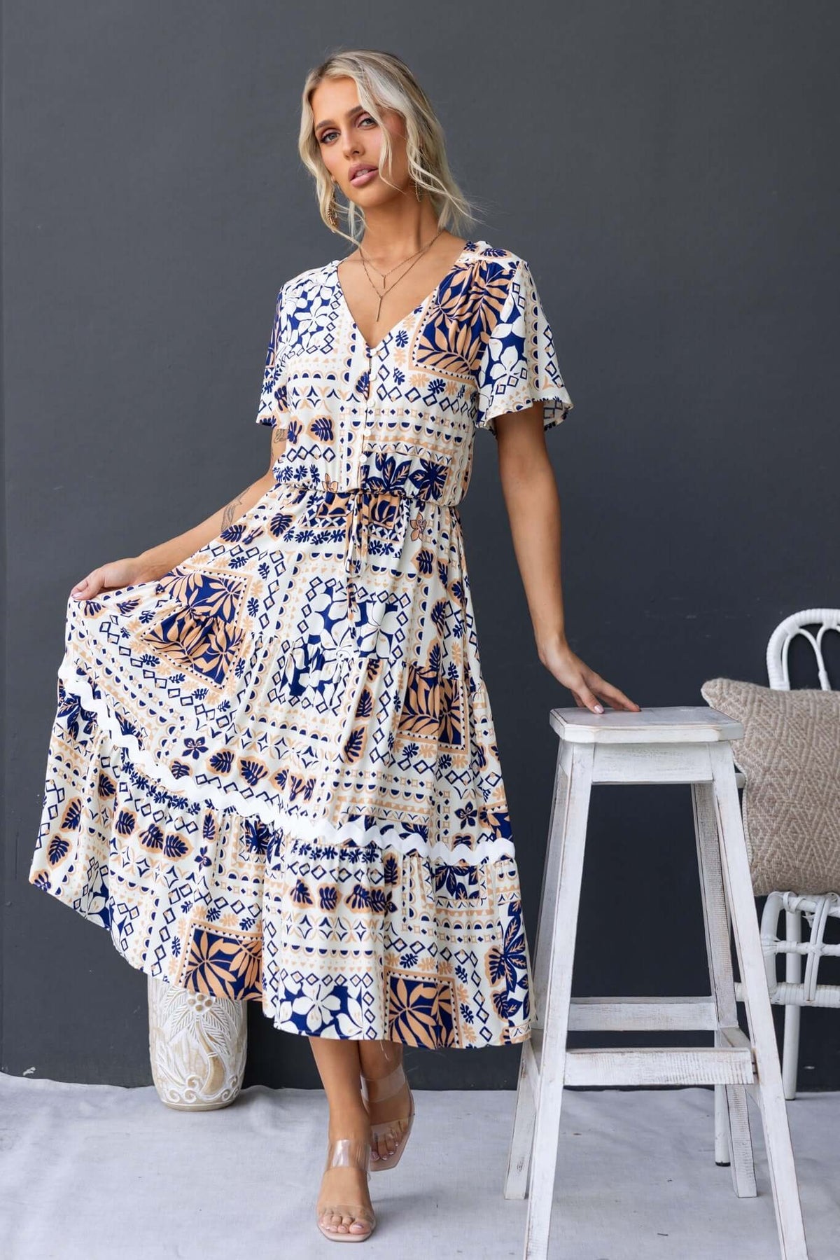 Model wearing the Virden Midi Dress featuring a V-neckline, button-up front, and pockets, against a neutral background.