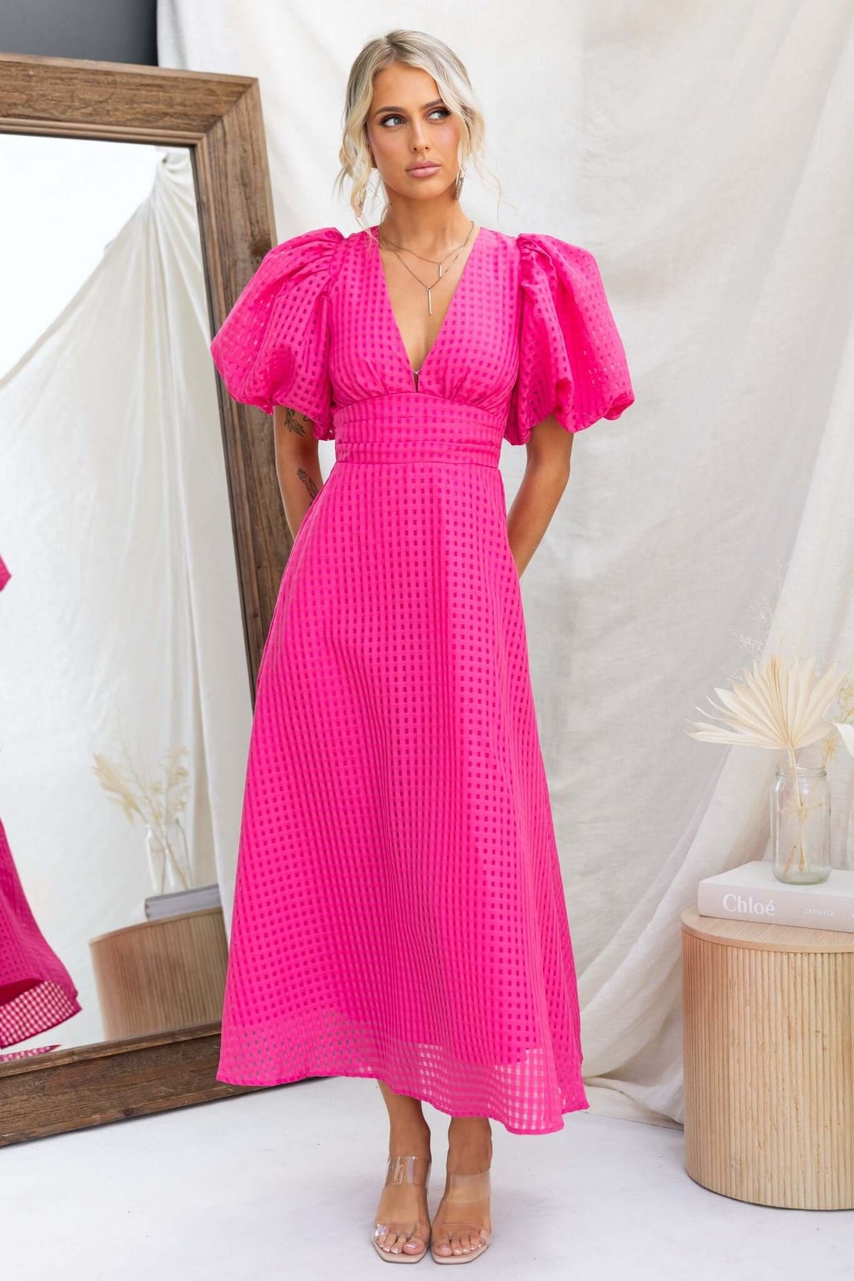 Nosita Midi Dress in vibrant pink with V-neckline, puff sleeves, and textured fabric, featuring pockets and a back zip.