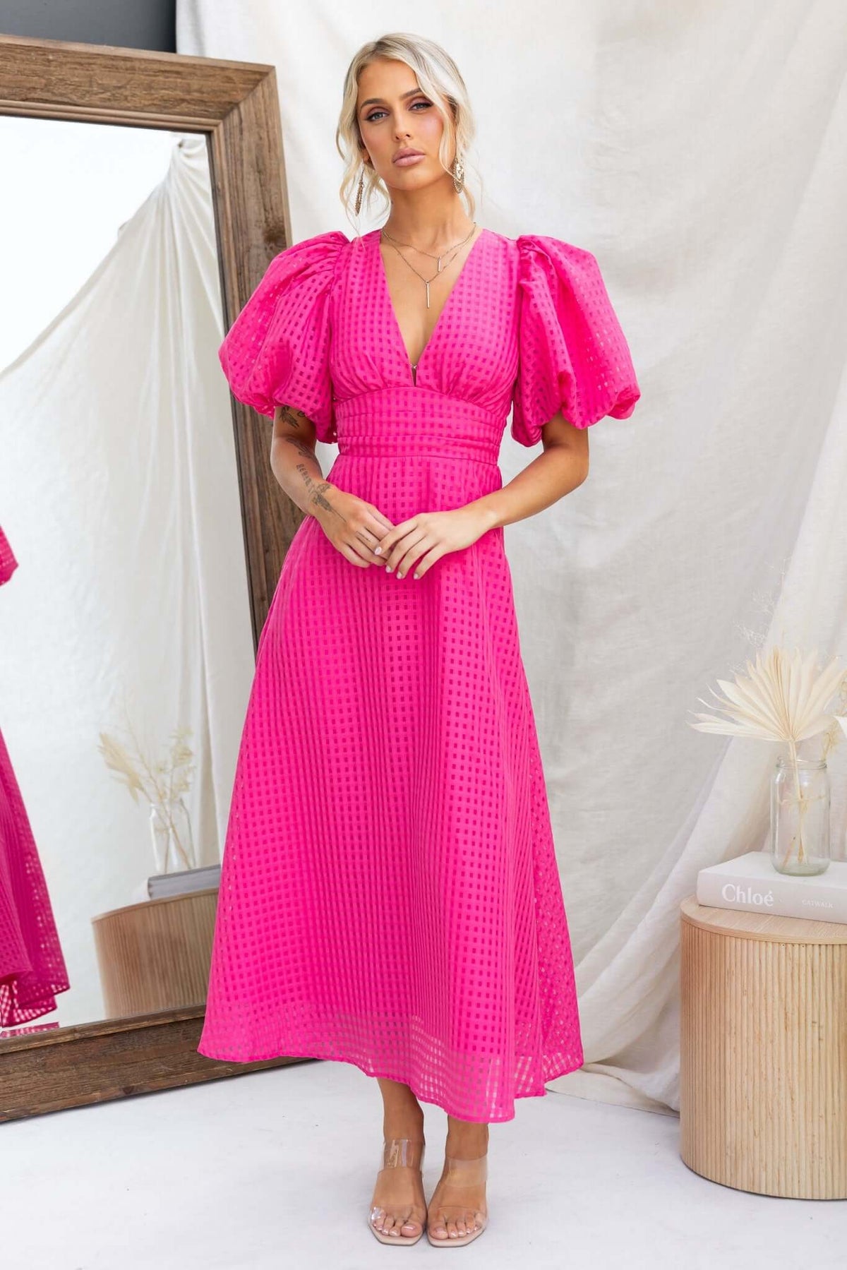 Nosita Midi Dress in vibrant pink with puff sleeves, V-neckline, and textured fabric, featuring an invisible zip and pockets.