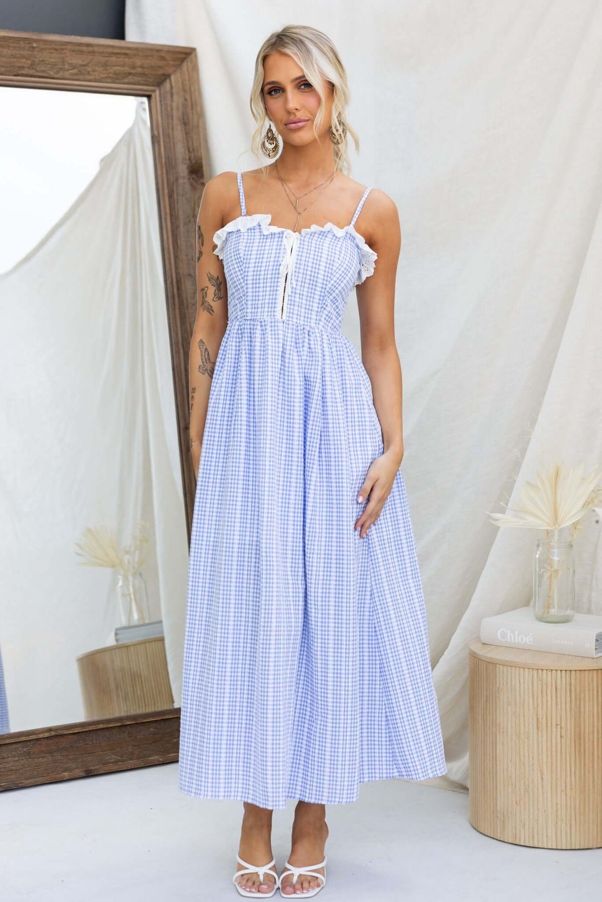 Model wearing the Endlessly Maxi Dress with adjustable straps and a blue gingham pattern, styled in a bright indoor setting.