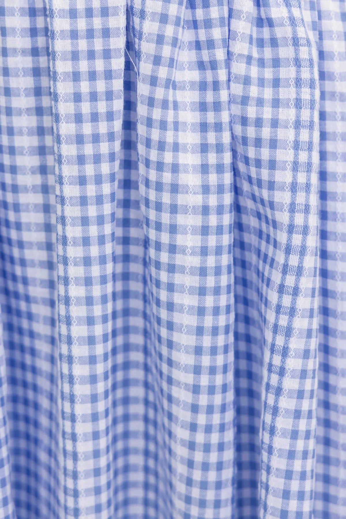 Close-up of light blue and white checkered fabric with pleats, ideal for a stylish maxi dress.