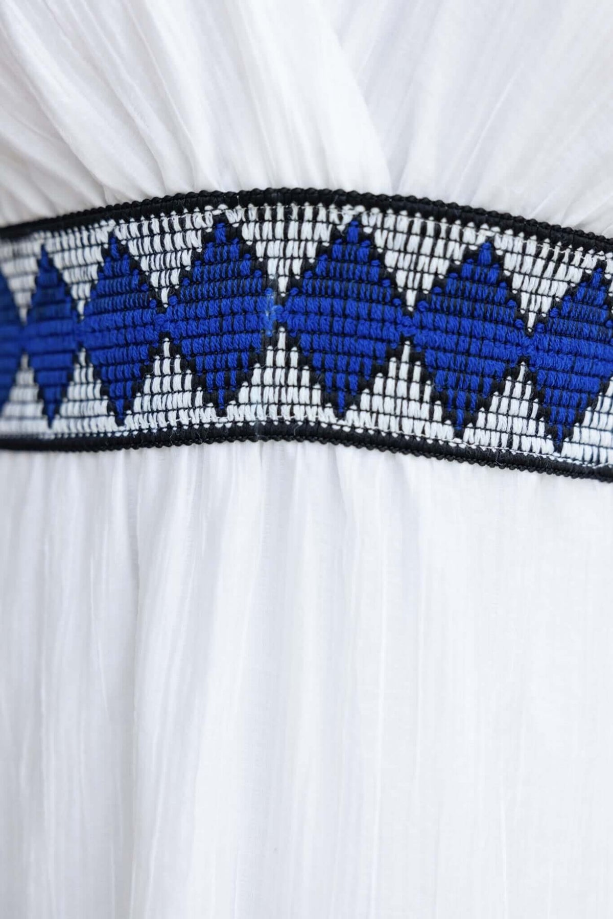 Close-up of blue and black patterned waistband on a white chiffon maxi dress.