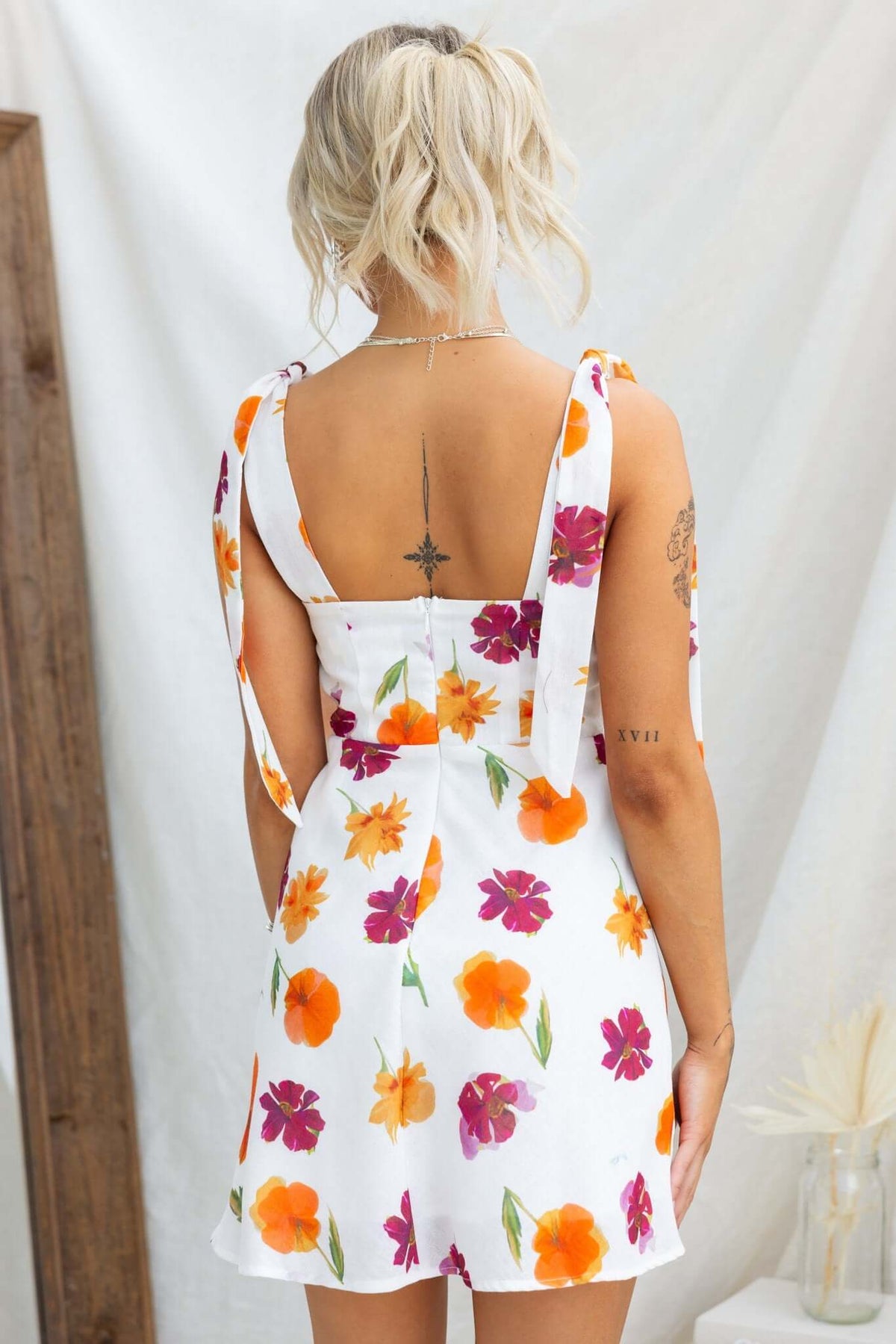 Back view of Kinsey Dress featuring floral print, adjustable tie straps, and light cotton fabric.