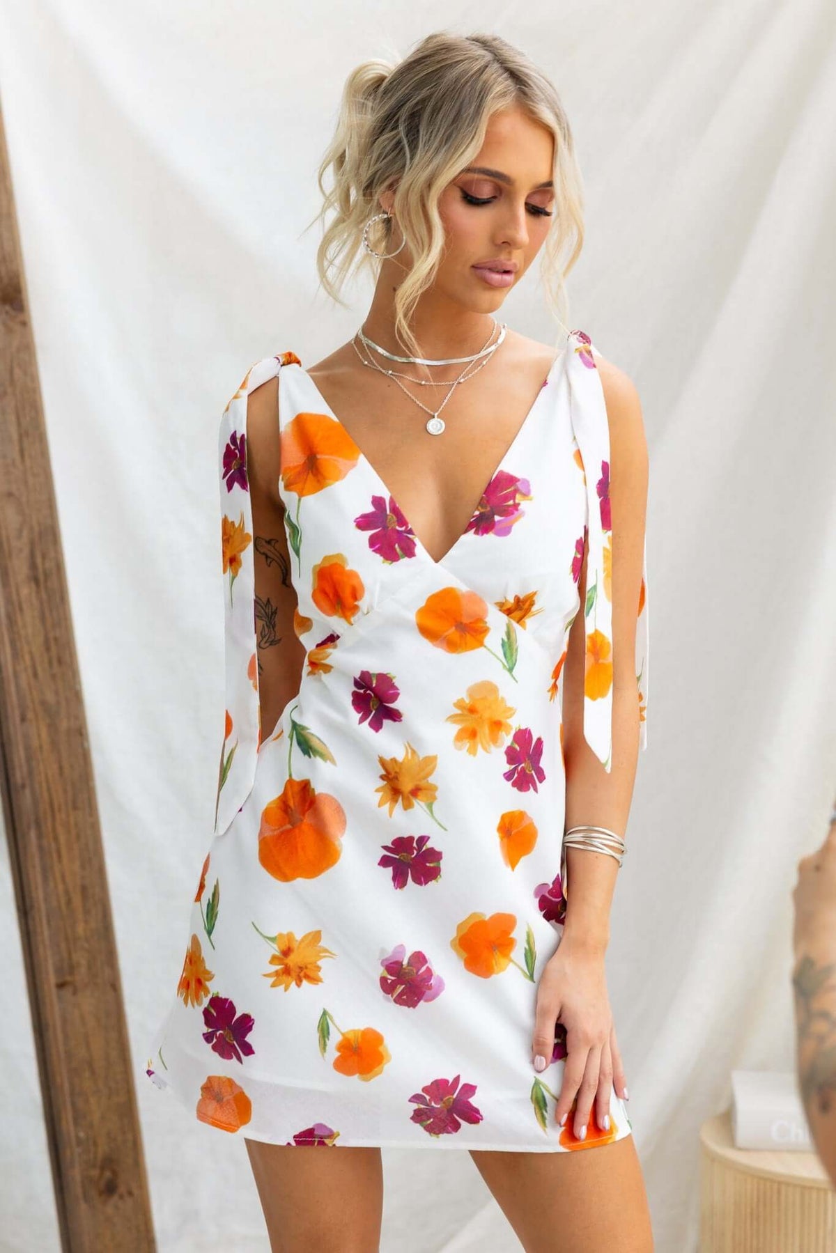 Floral print Kinsey dress with adjustable tie straps and a light cotton feel, modeled in a bright setting.