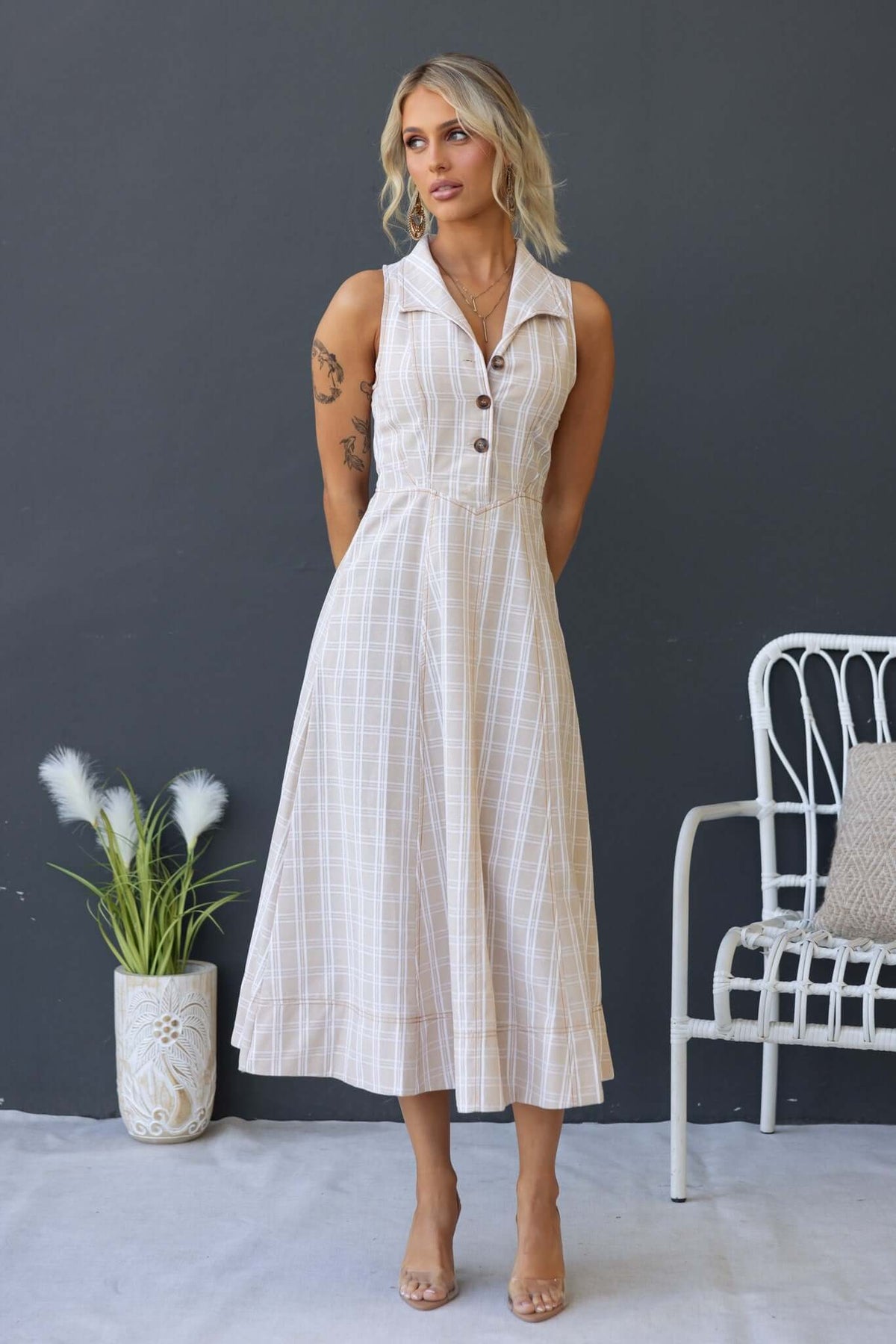 Model wearing a Harloh Midi Dress featuring a collar, button-up bust, and checkered pattern, styled in a modern setting.