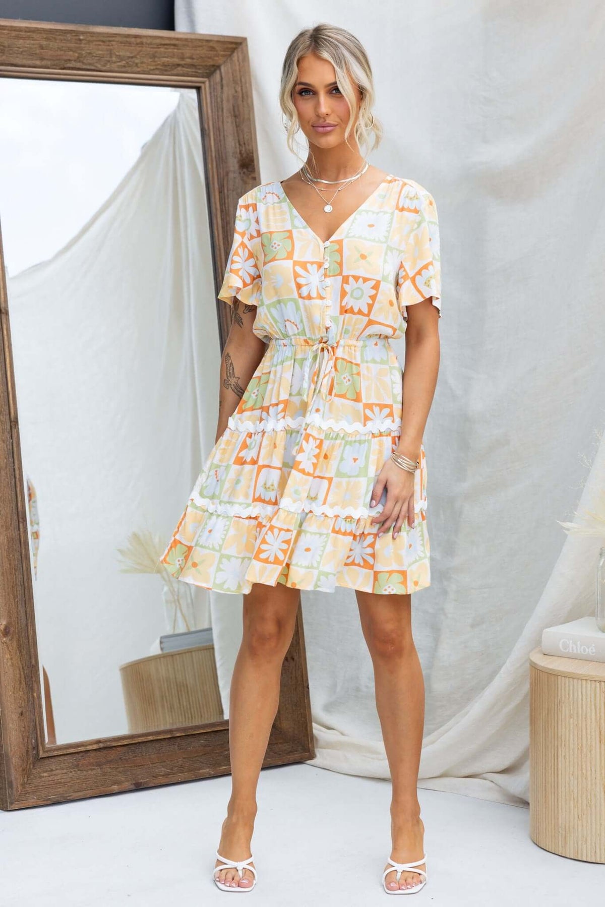 Virden Dress featuring a V-neckline, button-up bust, and elastic waistband with drawstring, styled with pockets.