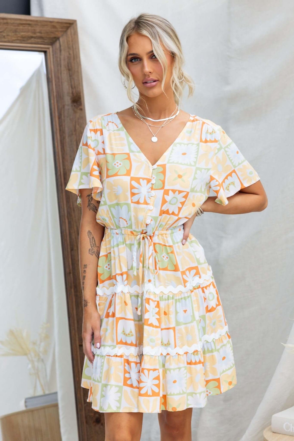 Virden Dress featuring a V-neckline, button-up bust, and elastic waistband with drawstring, displayed in vibrant floral patterns.