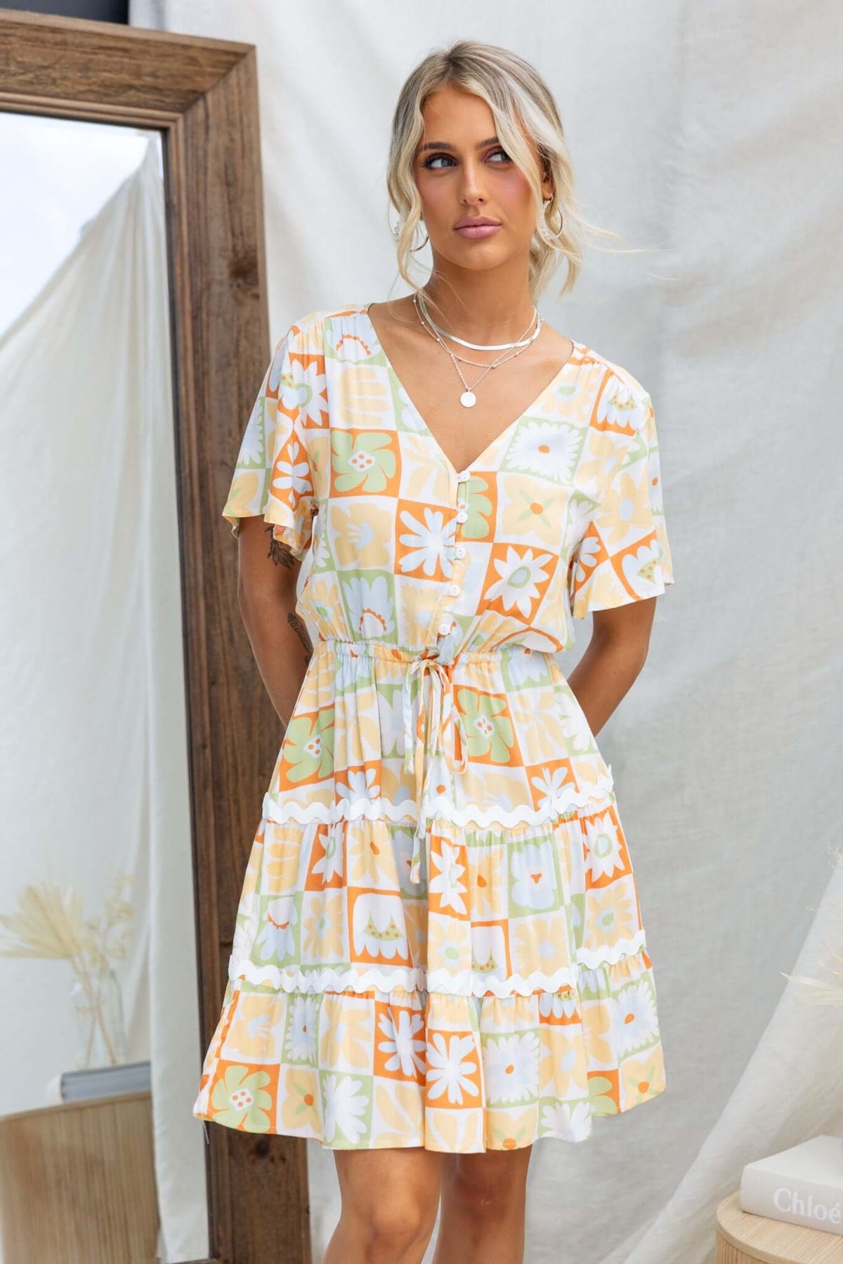 Virden Dress in vibrant floral print with V-neckline, button-up bust, elastic drawstring waist, and pockets.
