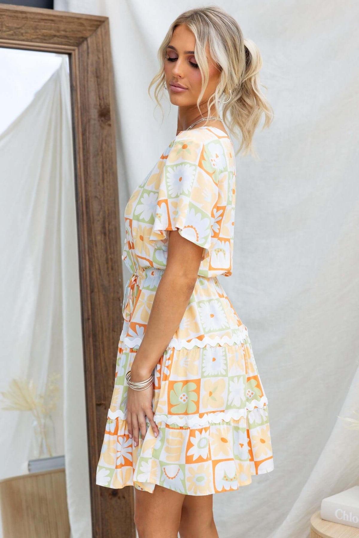 Model wearing a vibrant Virden Dress with V-neckline, elastic waistband, and floral pattern.