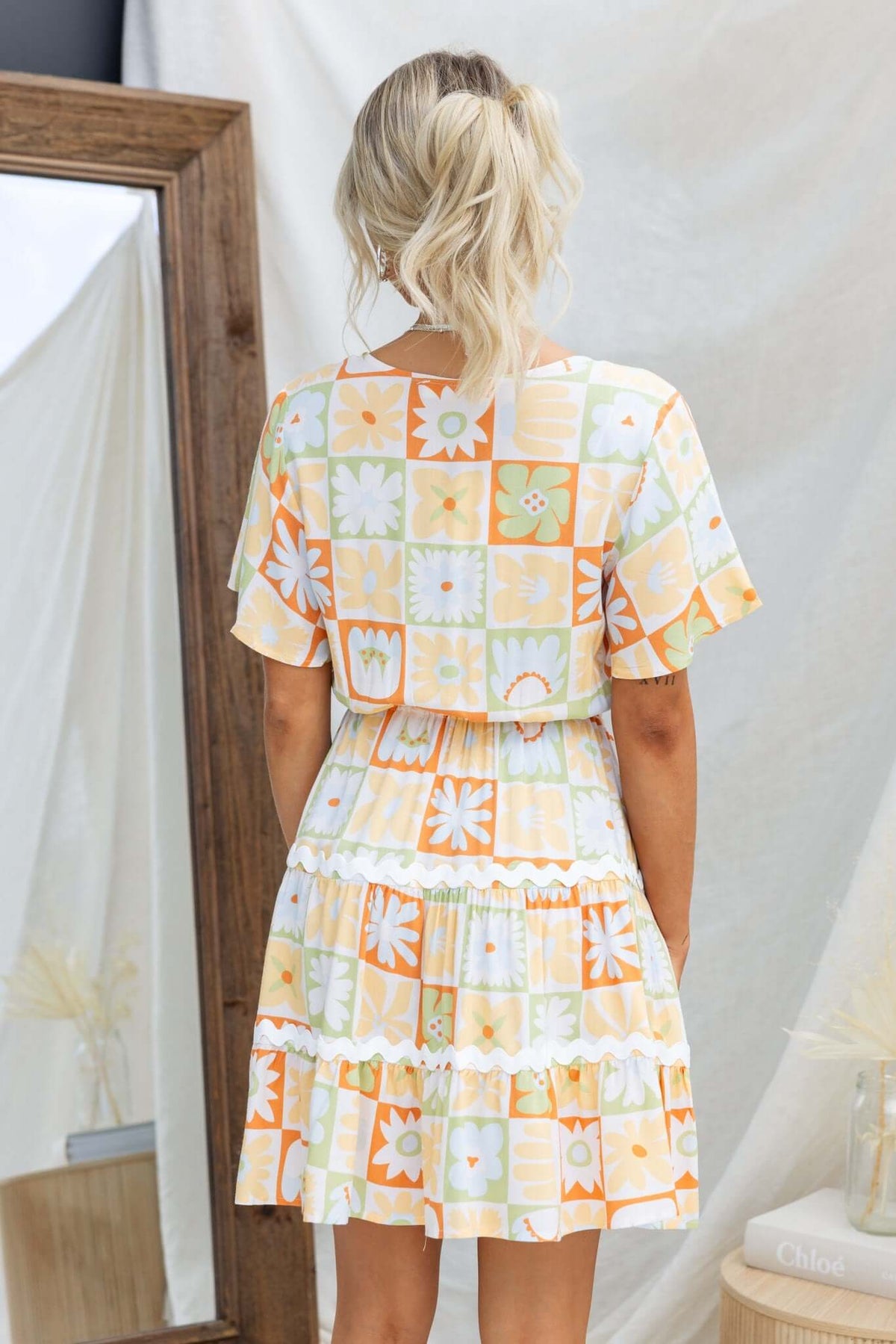 Back view of a woman in a floral-patterned dress with ruffles and short sleeves, showcasing a relaxed fit.
