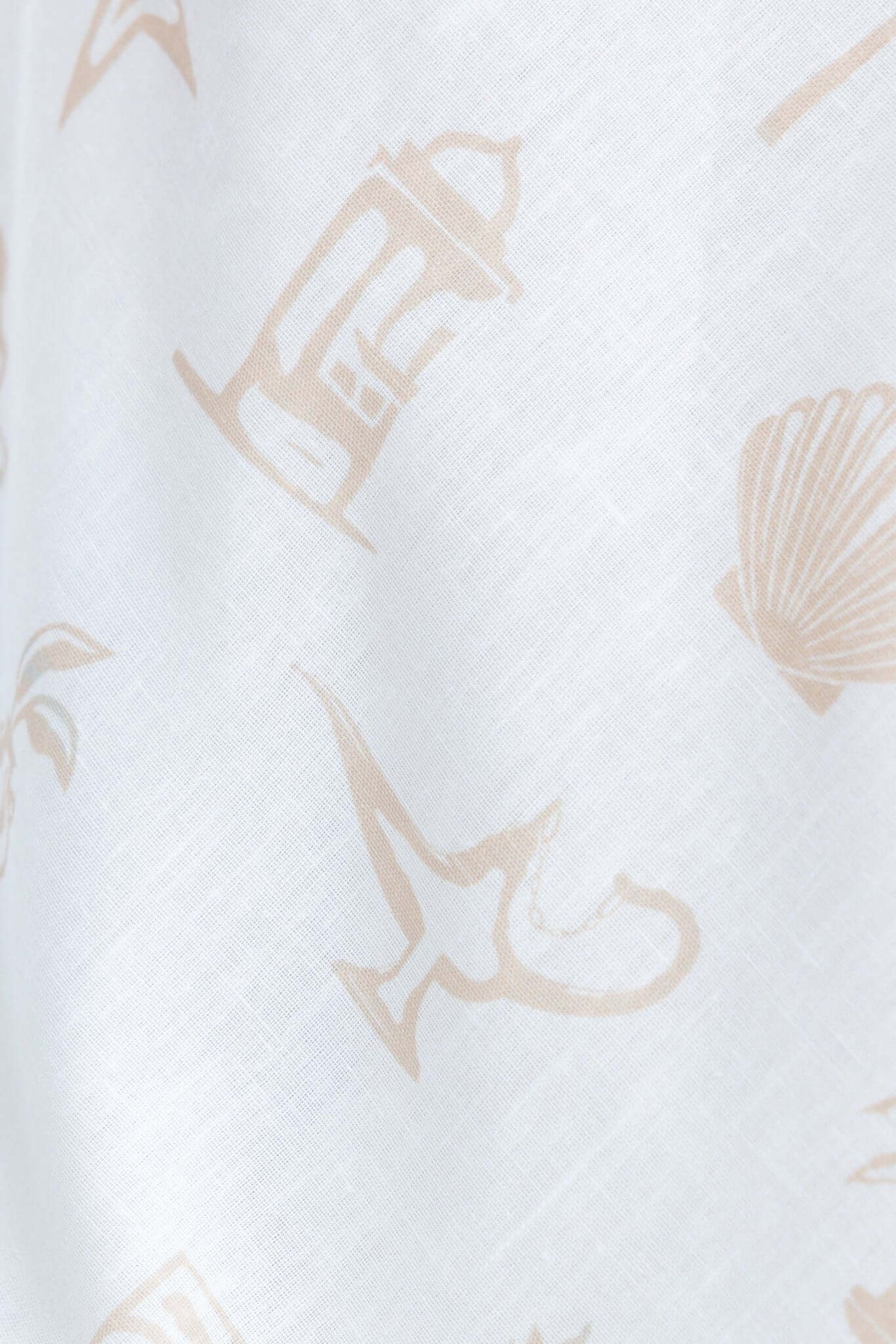 Close-up of Djuna Dress fabric showcasing a light pattern of seashells and lanterns on a soft, linen-like background.