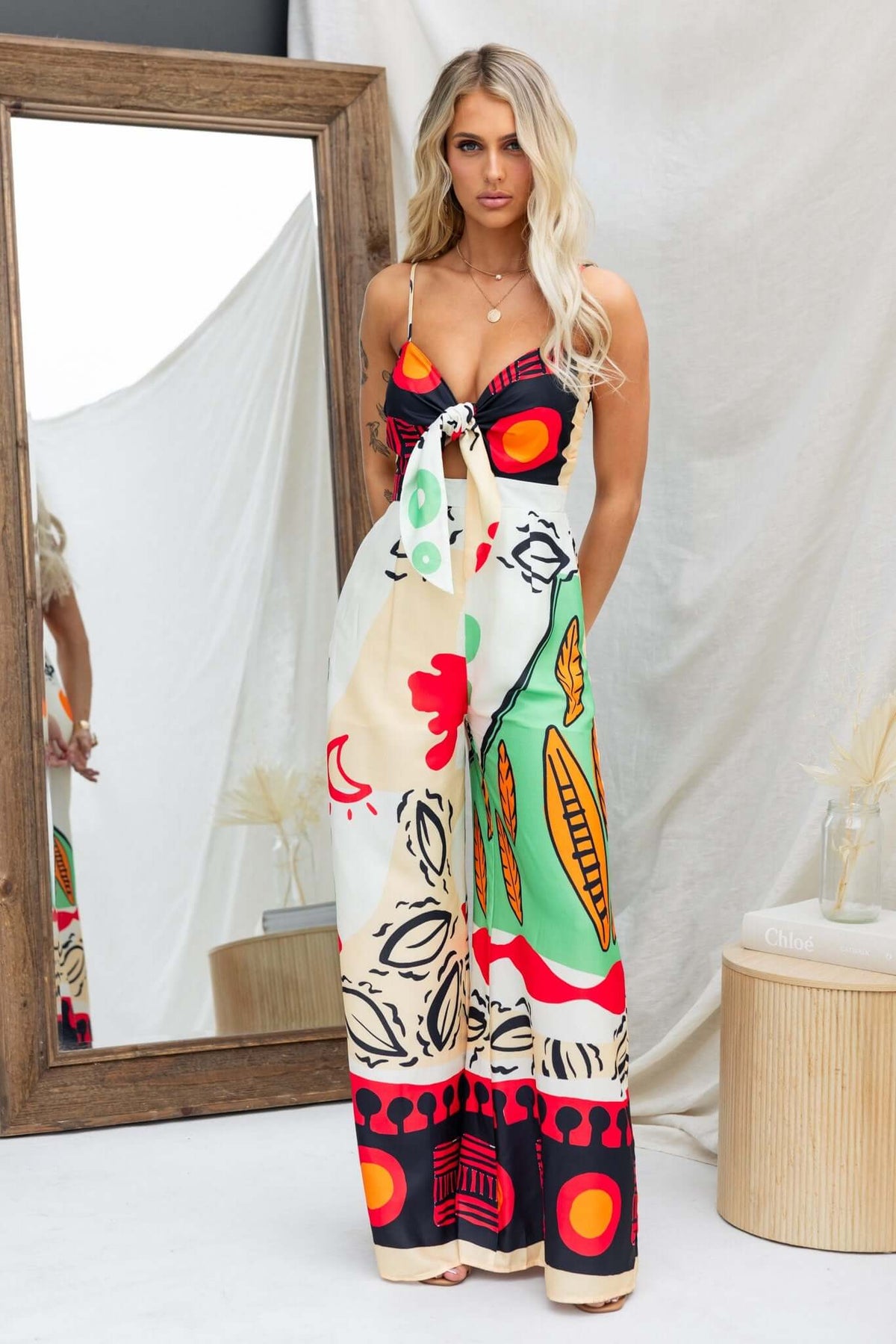 Multi-coloured print jumpsuit with adjustable straps, tie bust, pockets, and a light material. Perfect for summer fashion.